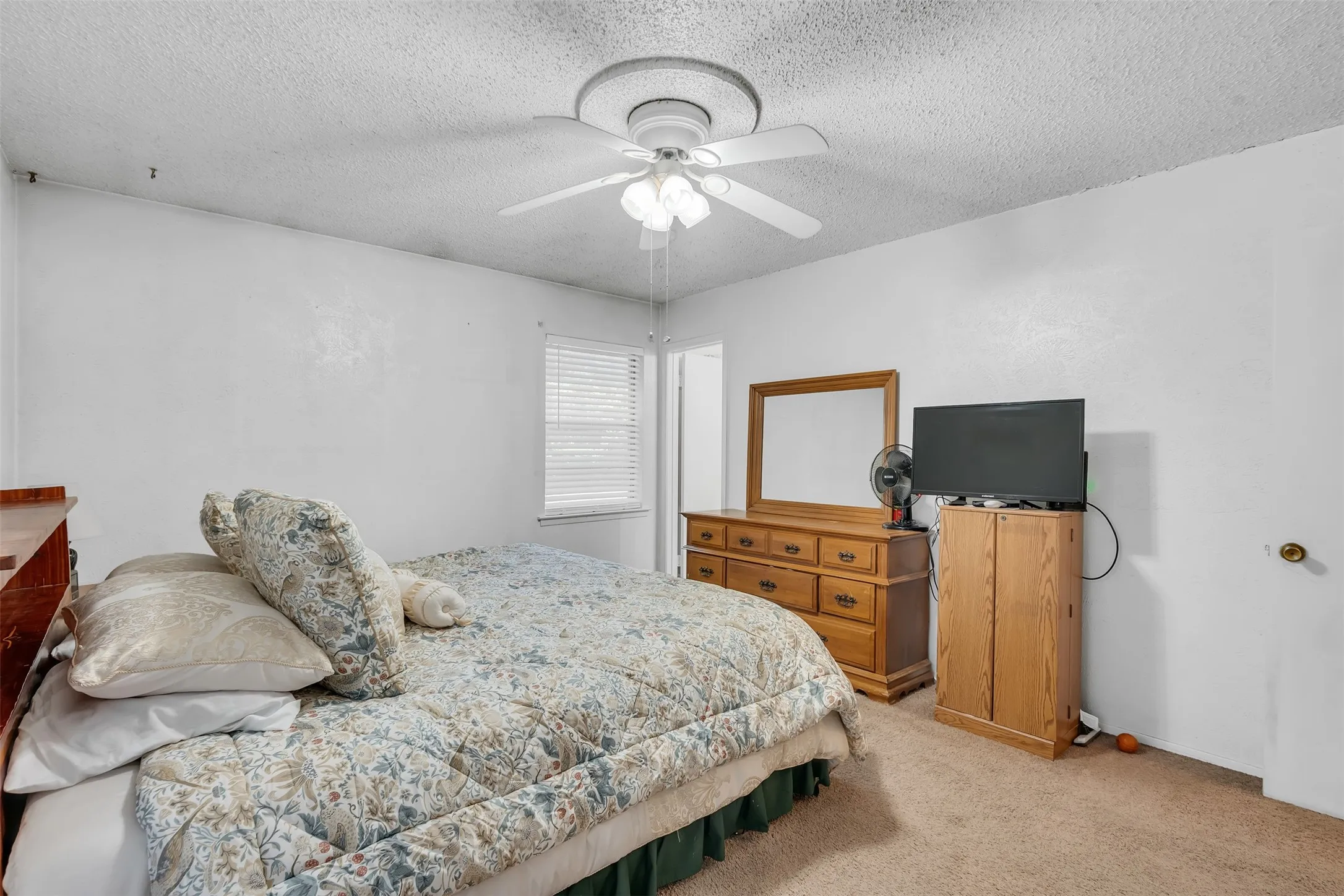 Carpeted bedroom featuring a ceiling fan, window with blinds, and white painted walls
