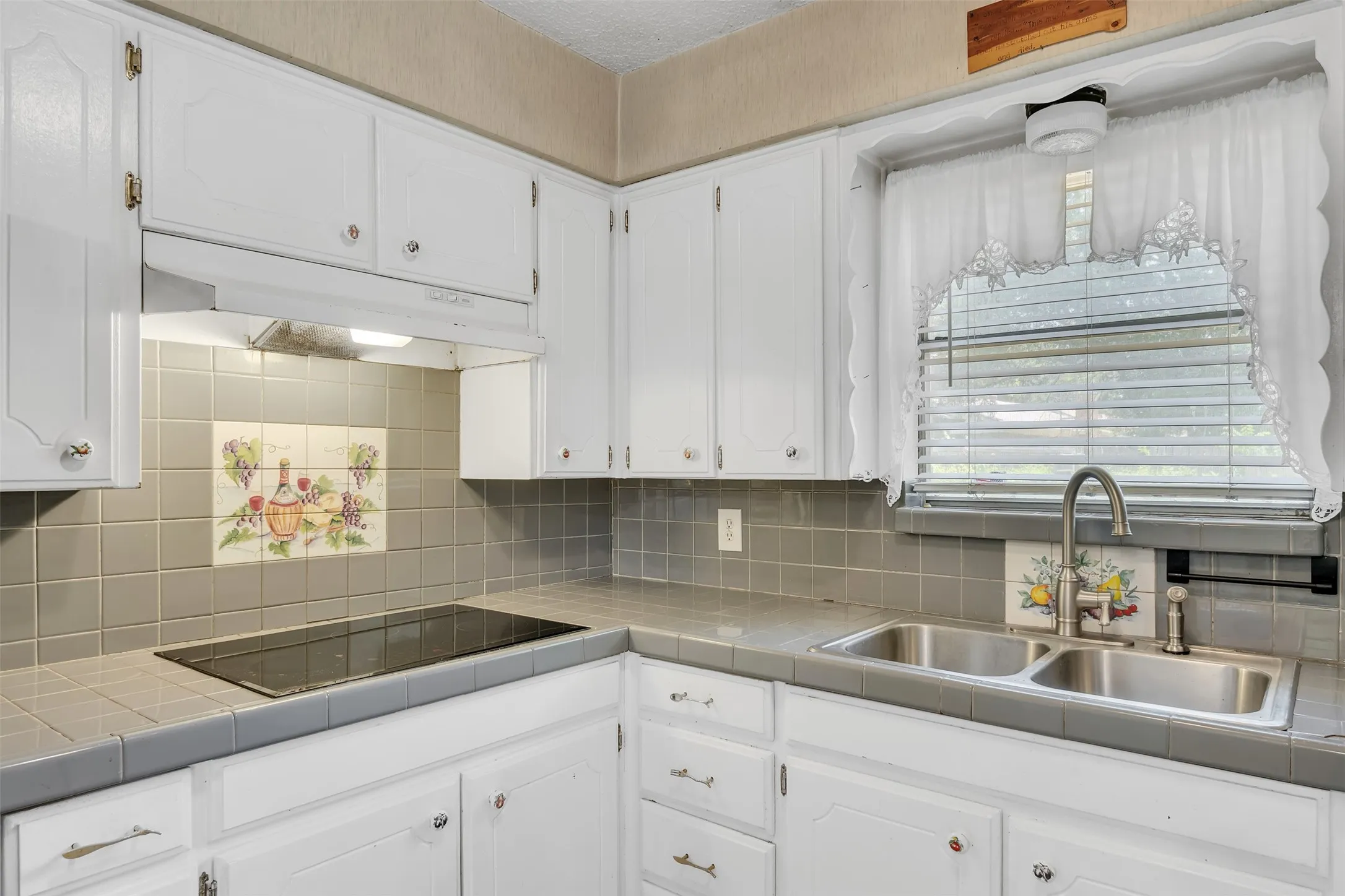 Kitchen featuring white cabinetry, gray tile countertops, and a gray tile backsplash