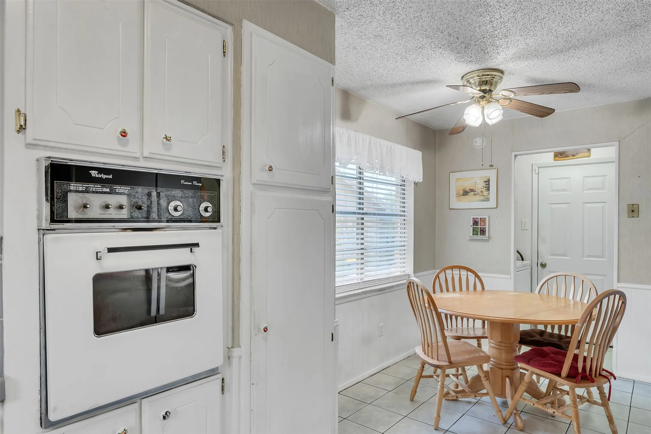 Kitchen area featuring white cabinetry, a built-in oven, and a ceiling fan