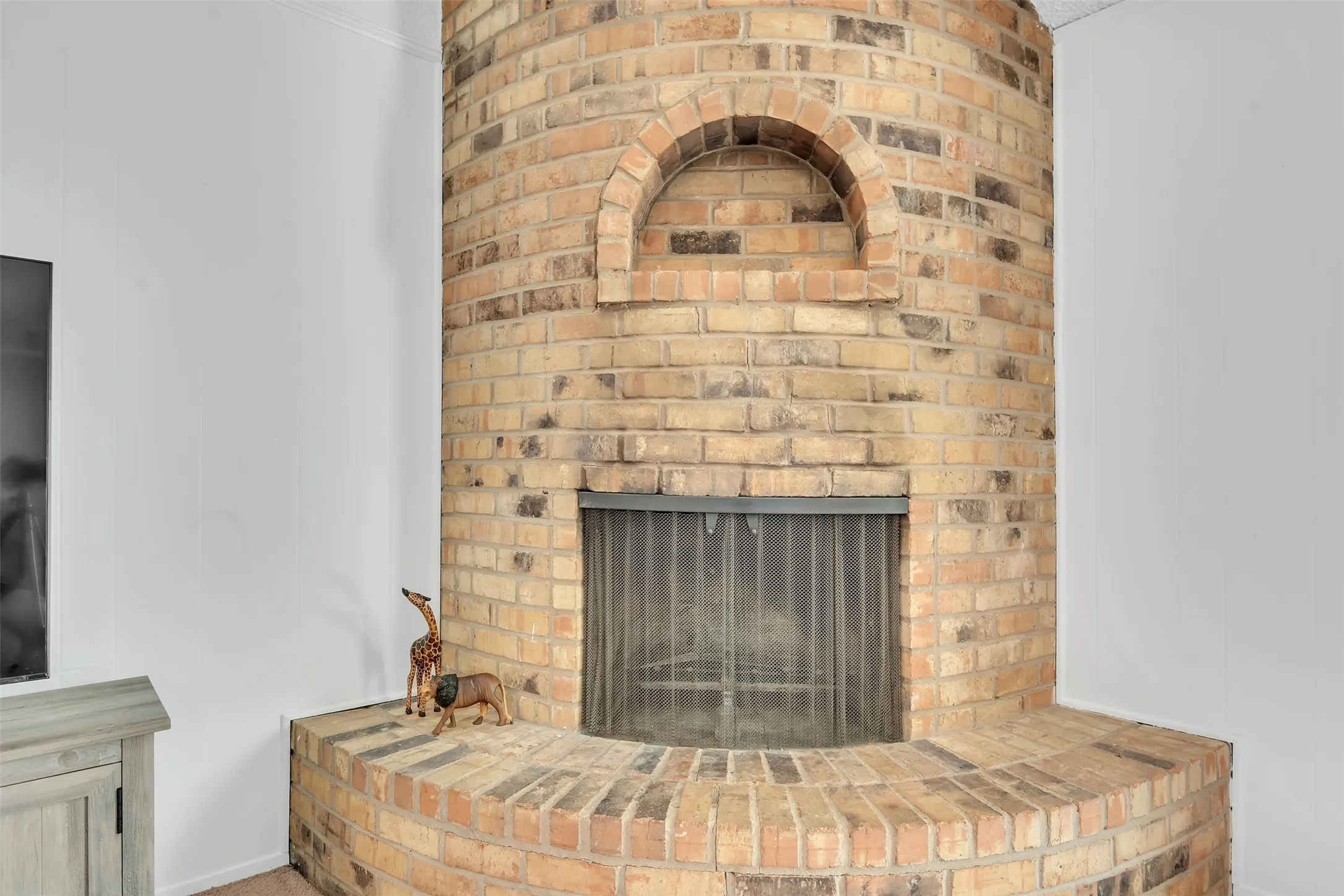 Brick fireplace with an arched niche, hearth, and fire screen