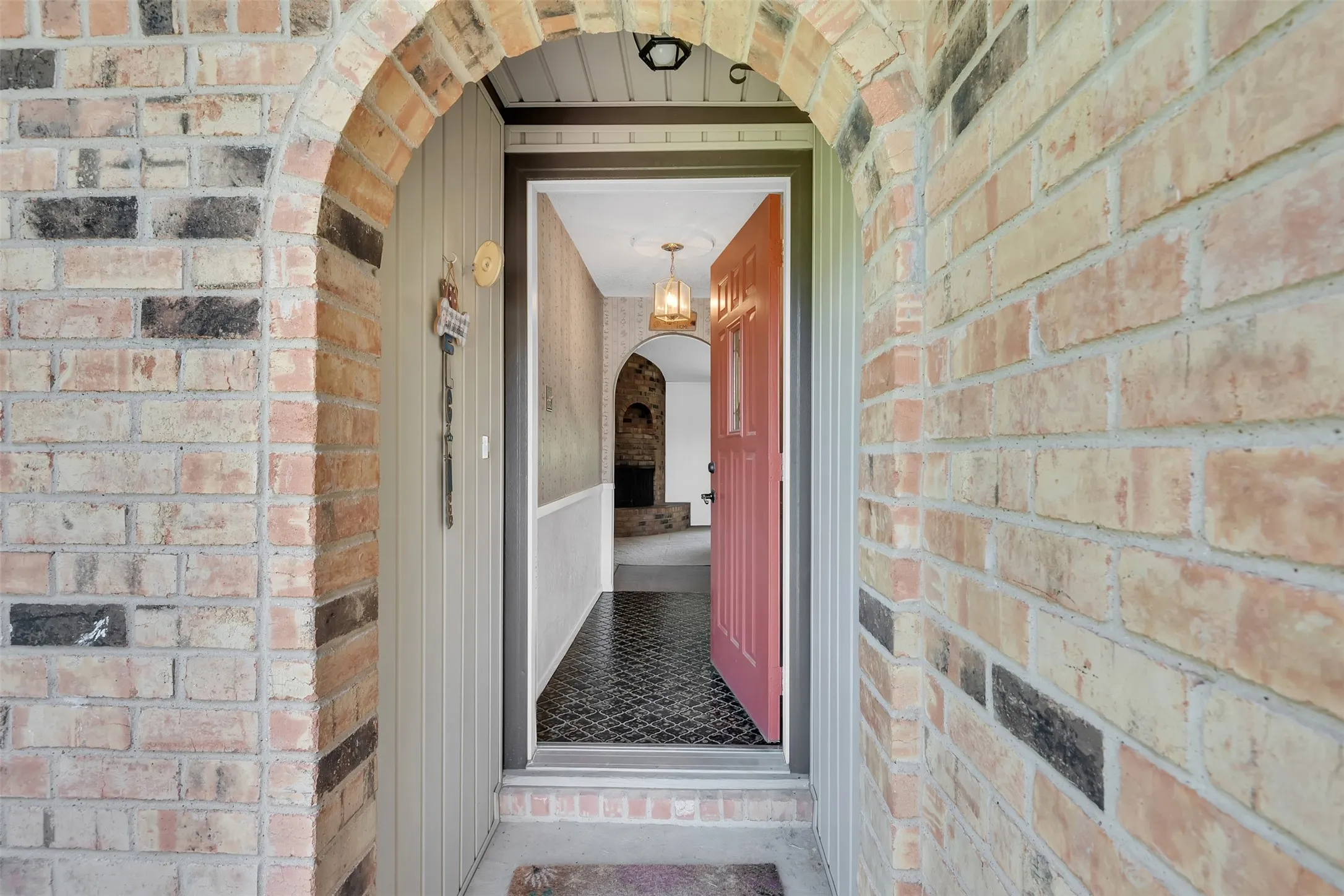 Brick archway entry with a red panel door