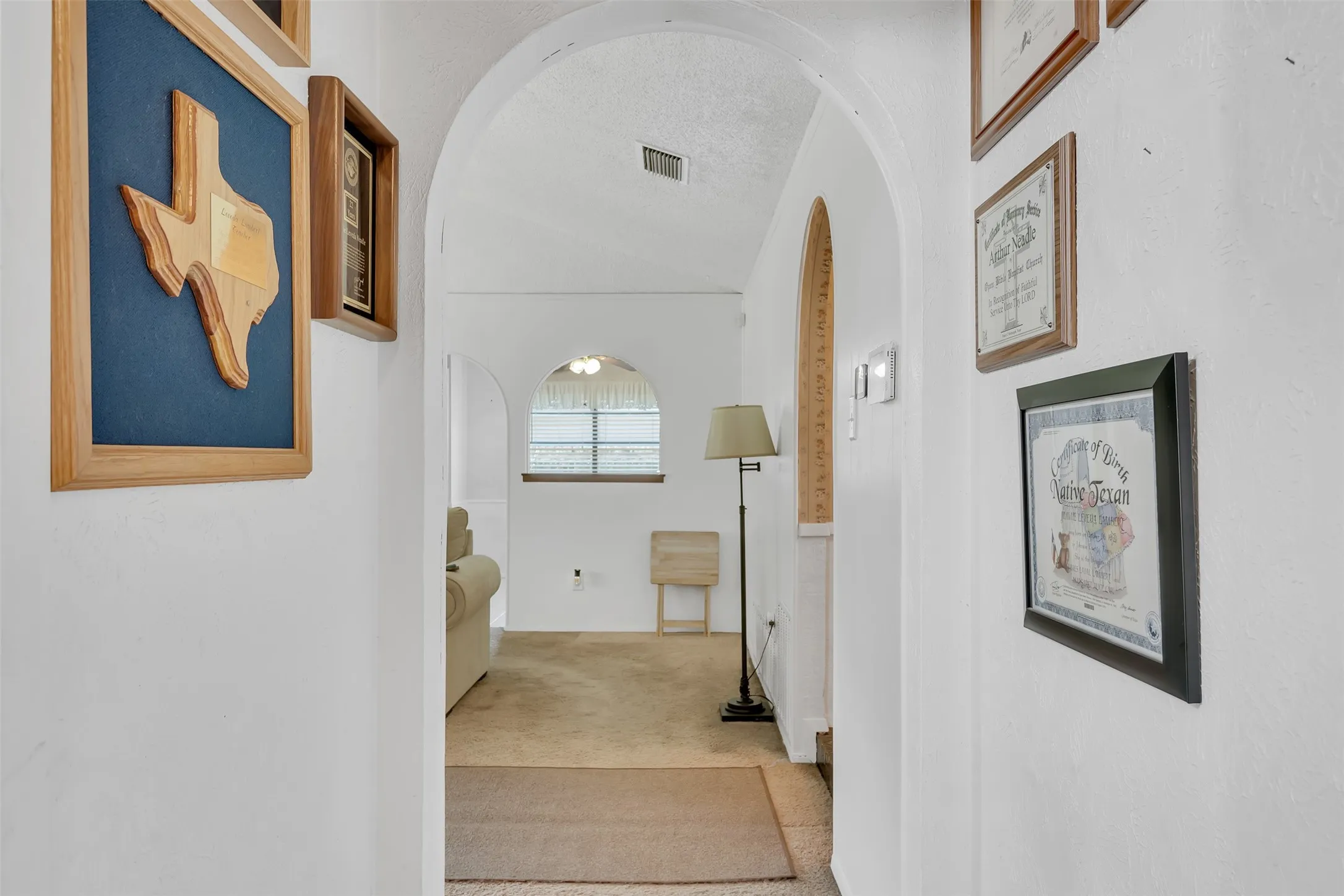 Archway entryways with white textured walls and light-toned carpet flooring