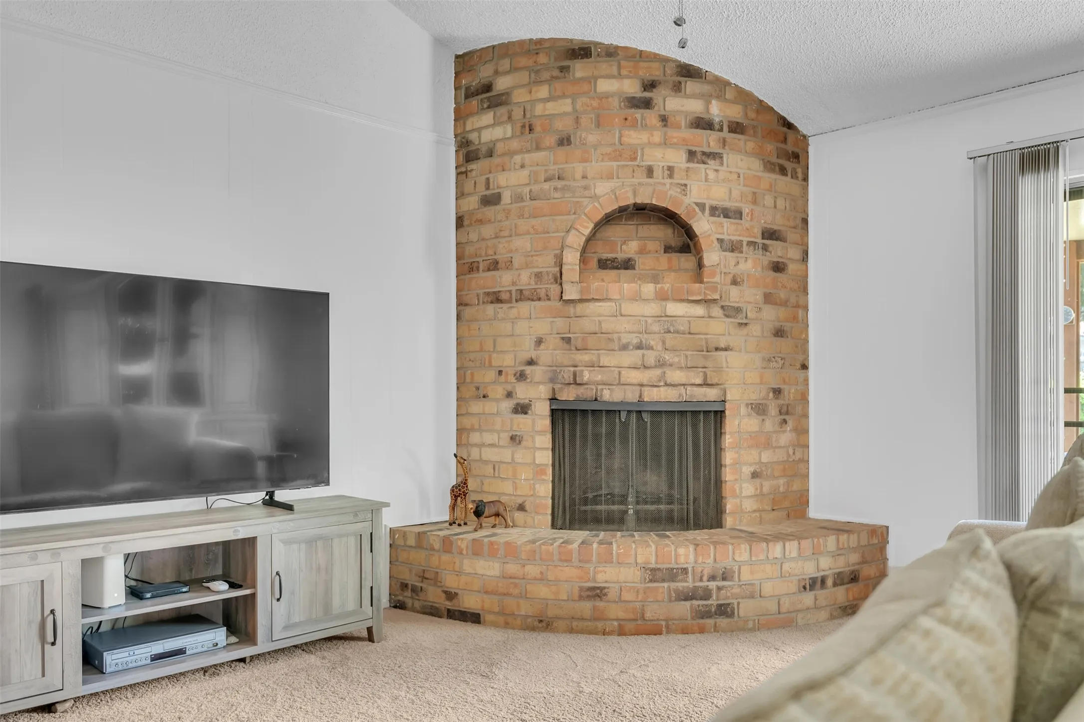Curved brick fireplace with an arched niche and integrated hearth, featuring a metal fireplace screen