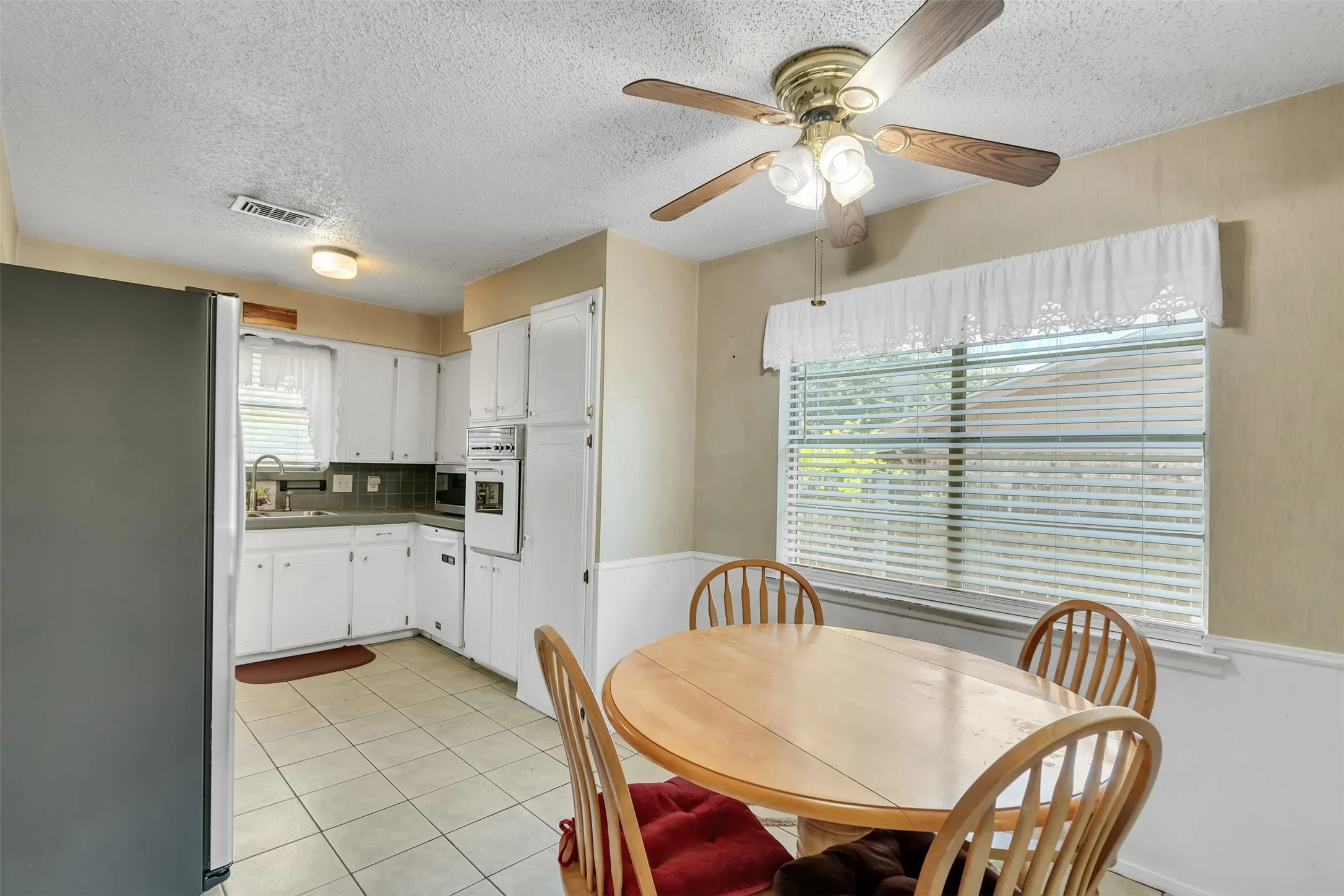 Kitchen featuring white cabinetry, tile flooring, a built-in oven, and a ceiling fan with light fixture