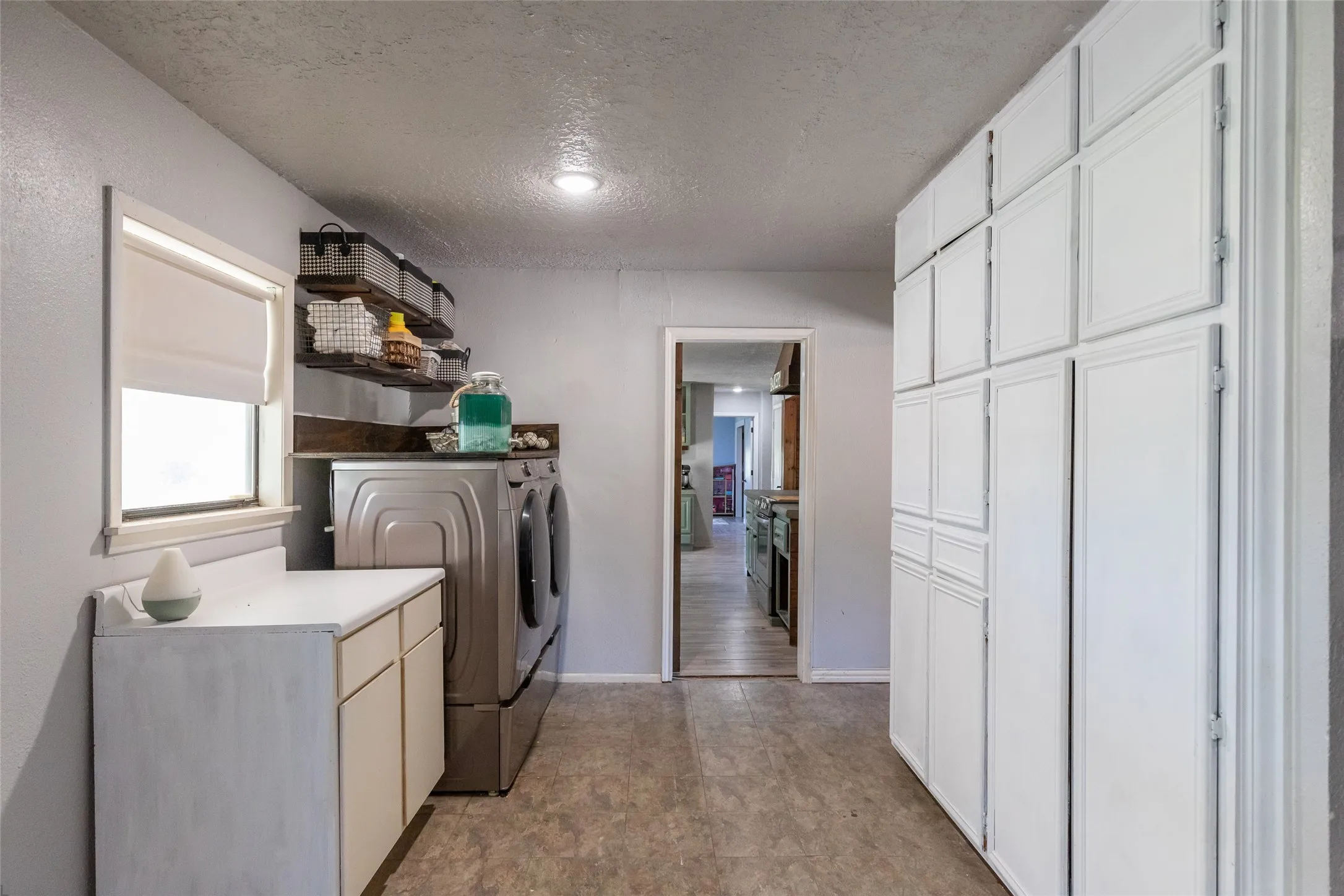 Dedicated utility space featuring extensive built-in cabinetry, a window with a roller shade, and a countertop area