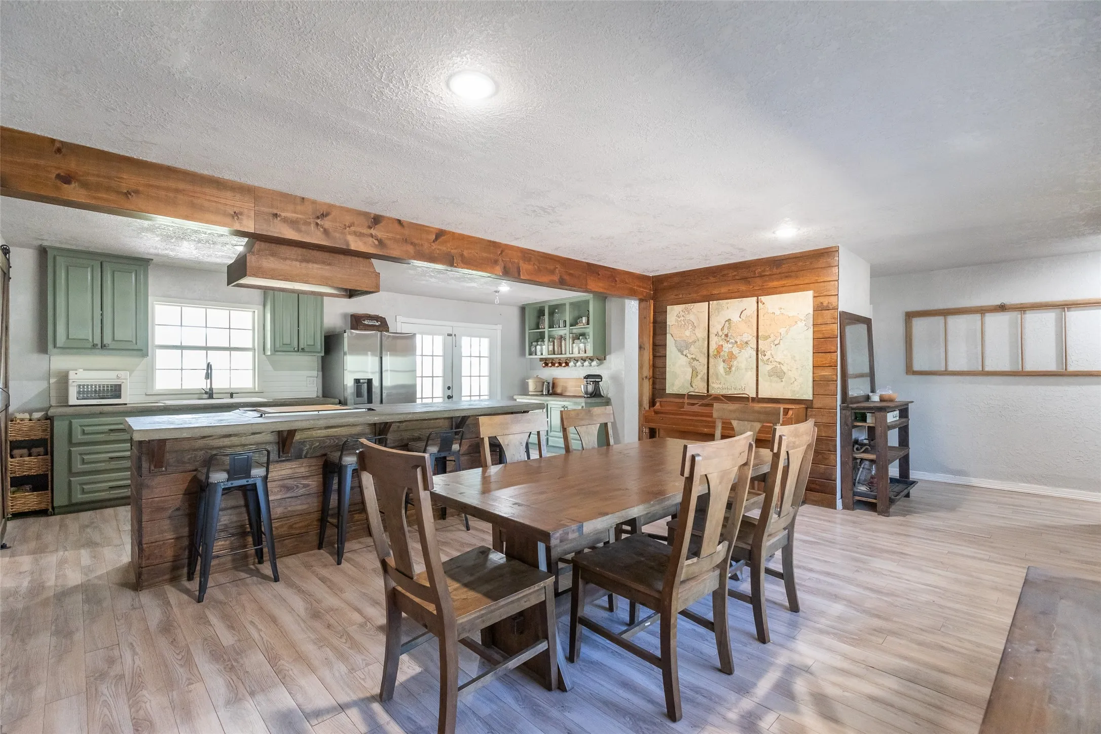 Open-concept living space featuring wood-finish flooring, exposed wood beams, and a wood-paneled wall accent