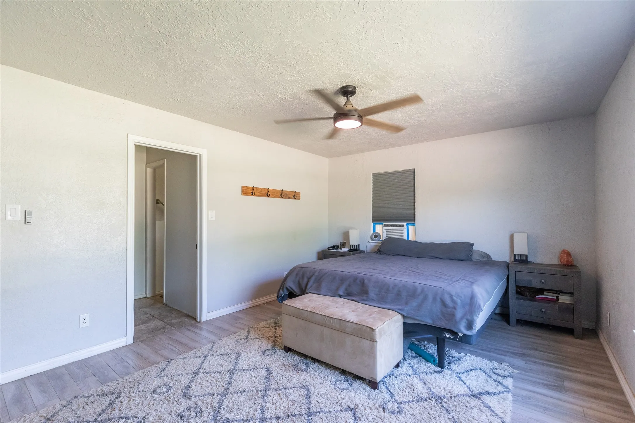 Spacious room featuring light wood-finish flooring, a ceiling fan with integrated lighting, and neutral wall tones