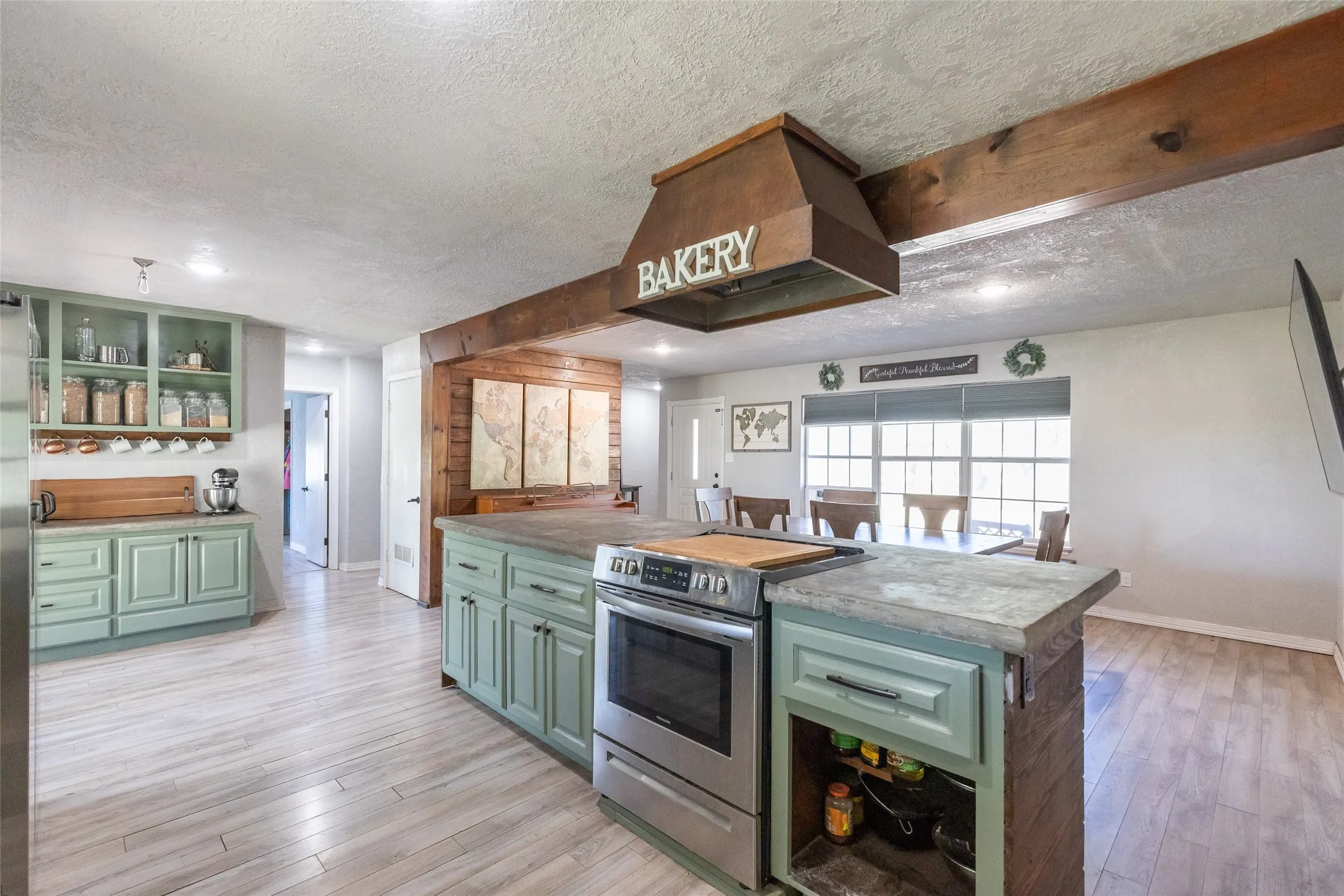 Kitchen featuring a central island with an integrated stainless steel range and a custom wood range hood