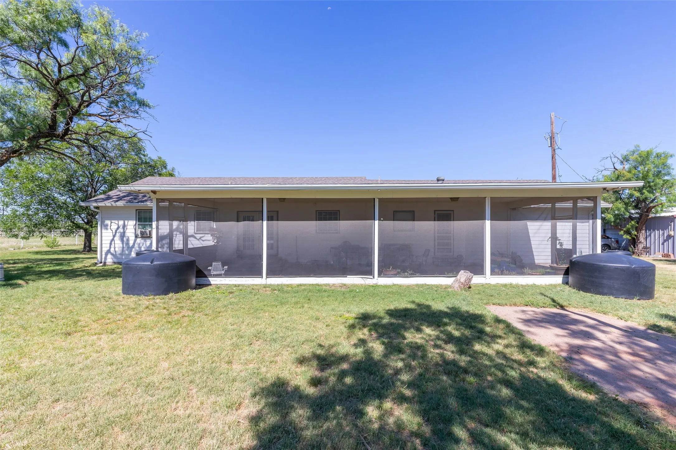 Rear exterior featuring a full-length screened porch, white siding, and a gabled roofline
