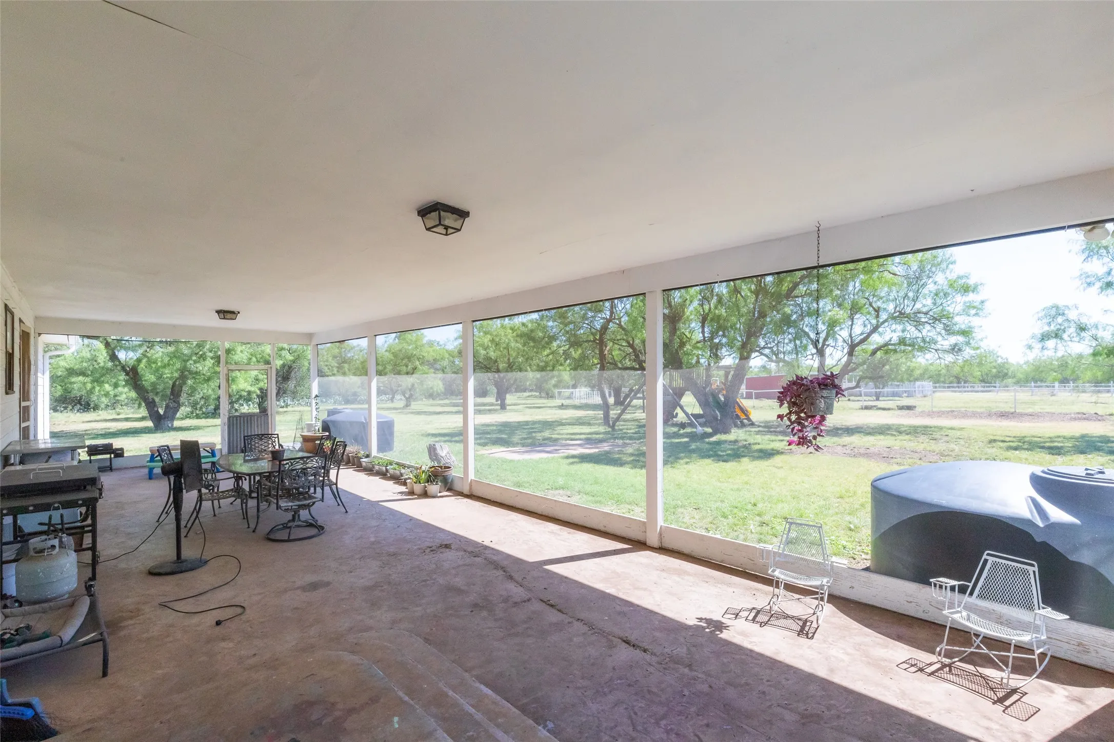 Expansive screened-in porch with concrete flooring and multiple ceiling-mounted light fixtures