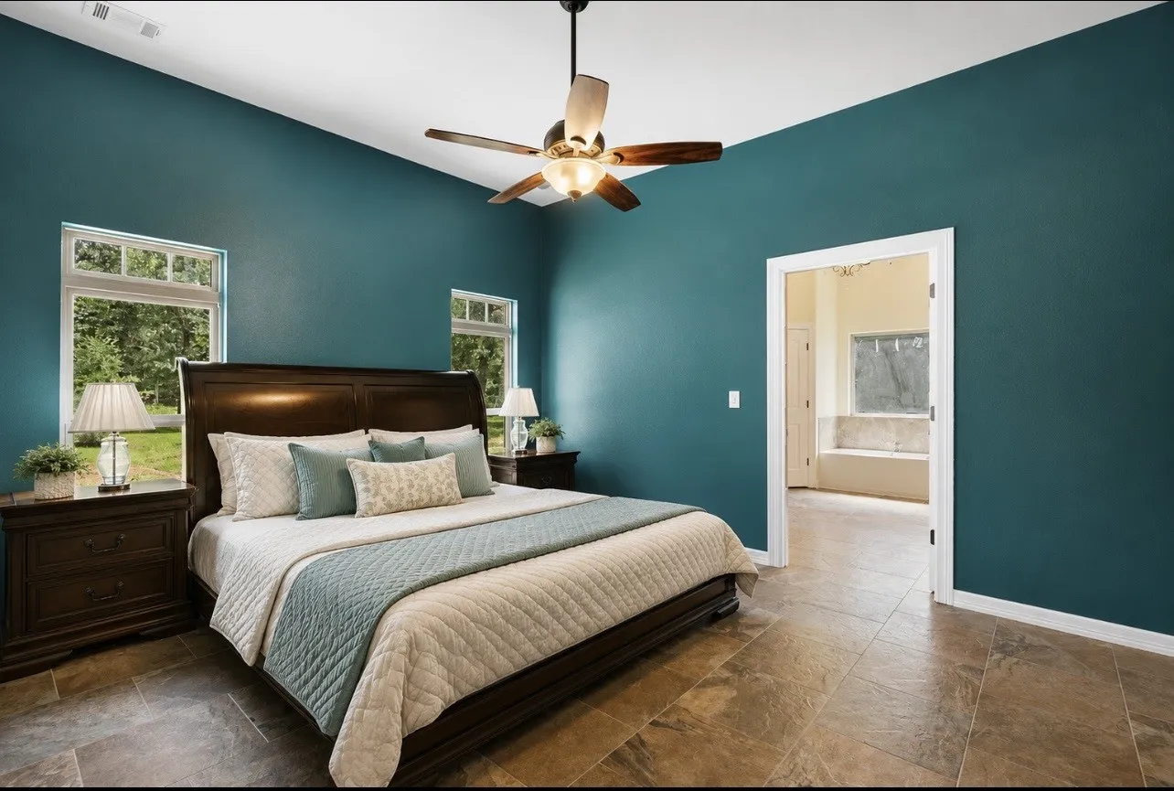 Spacious room featuring vaulted ceilings, a ceiling fan, and large windows with exterior green space visible