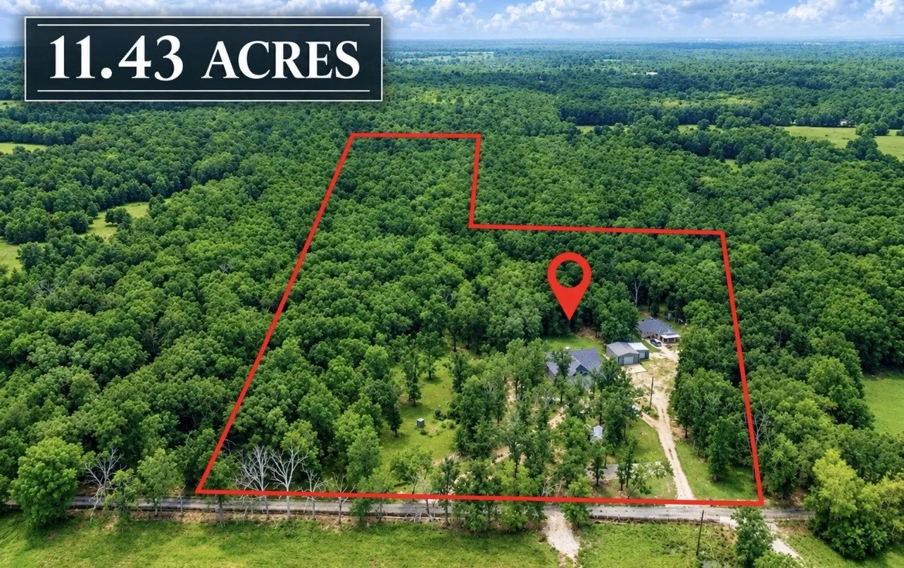11.43 acre parcel with abundant tree coverage, established buildings, and a clear boundary