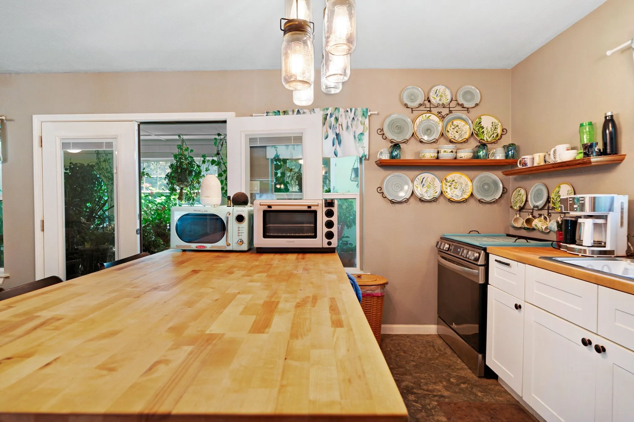 Expansive wood-finish island with a light tone, white cabinetry, integrated stainless steel range, wood-finish countertops, and dual glass-paneled doors