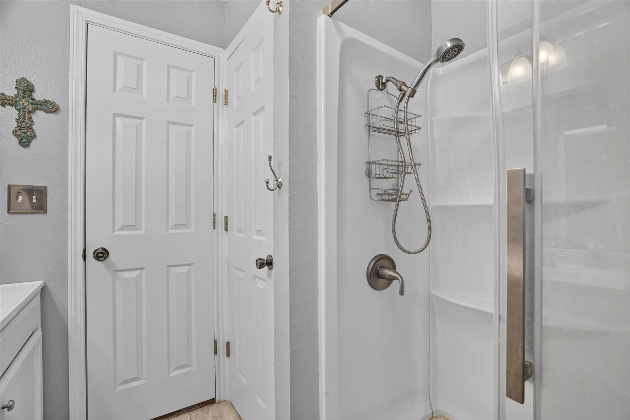 Walk-in shower with a glass enclosure, built-in shelving, and a bronze-finish showerhead