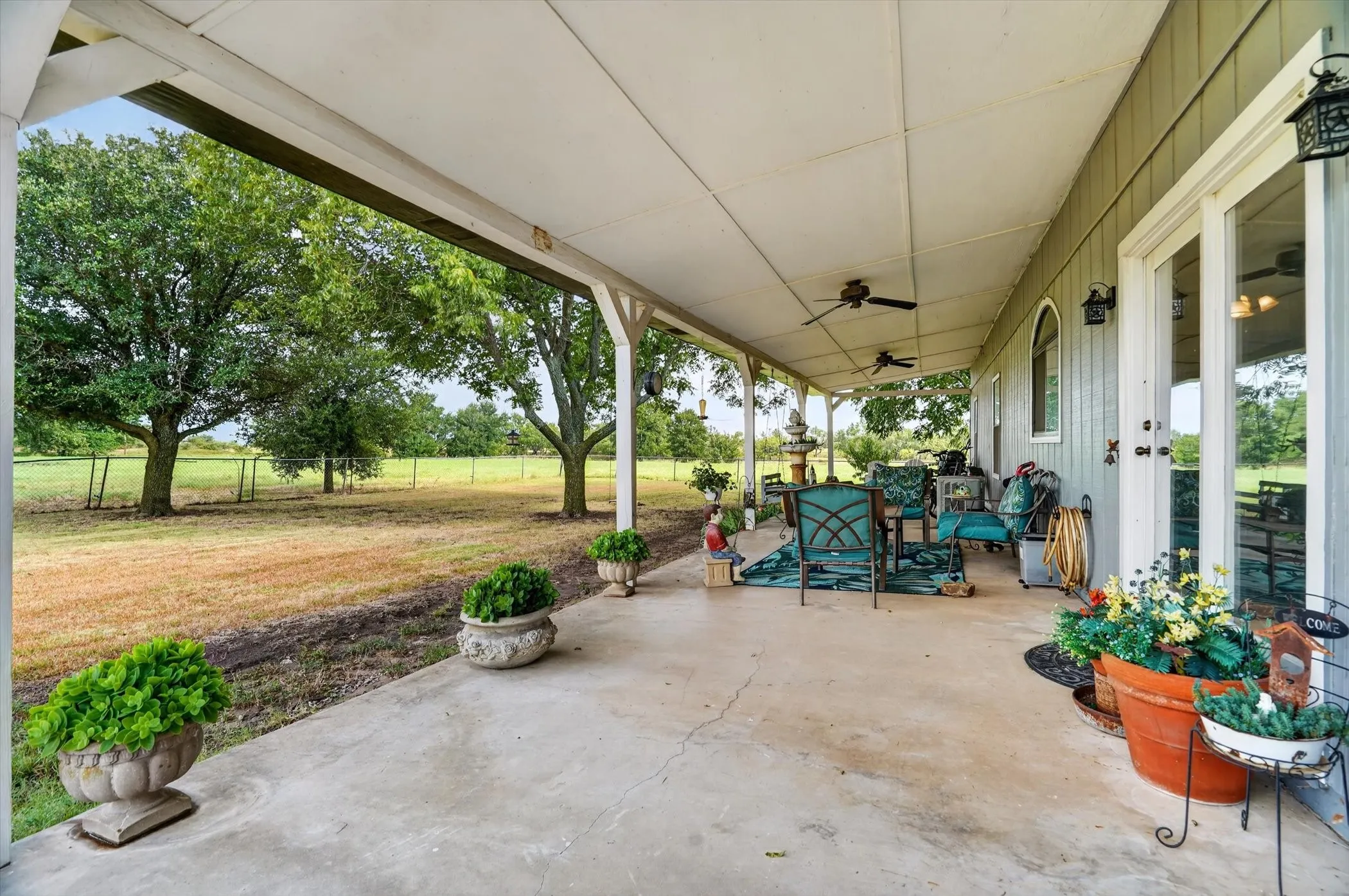 Expansive covered patio featuring a concrete surface and multiple ceiling fans
