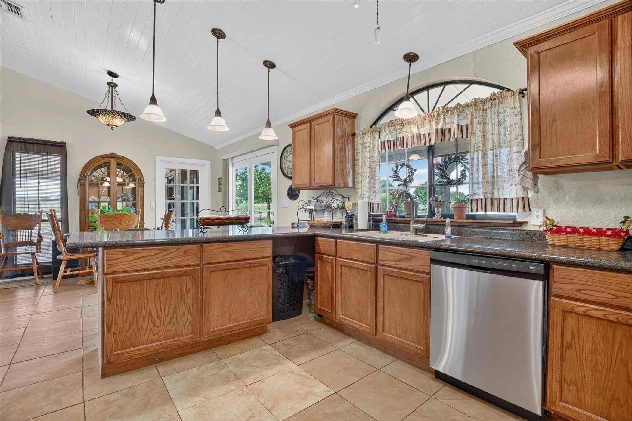Kitchen featuring warm wood cabinetry, dark speckled countertops, and stainless steel dishwasher