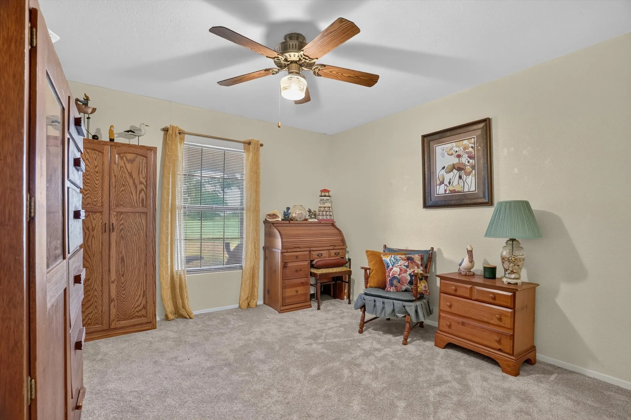 Carpeted room featuring a ceiling fan with integrated lighting, a window with exterior views, and neutral-toned walls