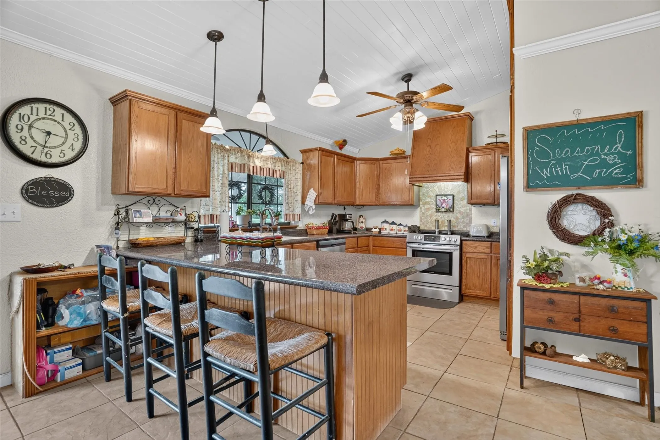 Kitchen featuring a large island with a stone countertop, wood cabinetry, stainless steel appliances, and tile flooring