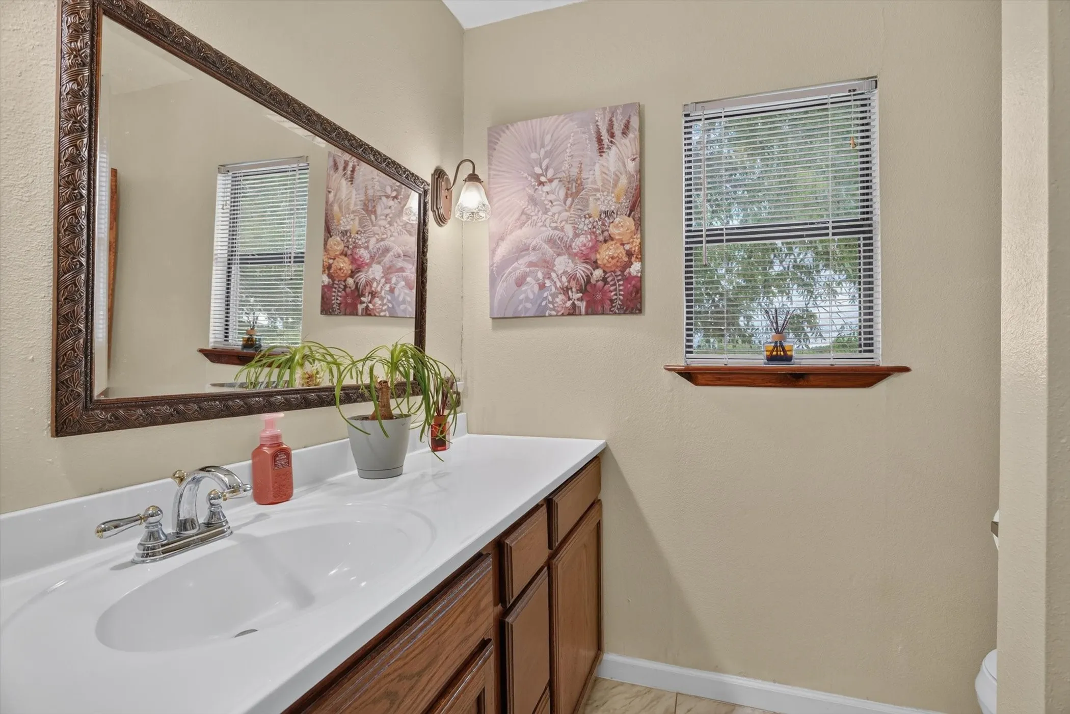 Vanity featuring a white countertop with an integrated sink, chrome faucet, and wood-finish cabinetry
