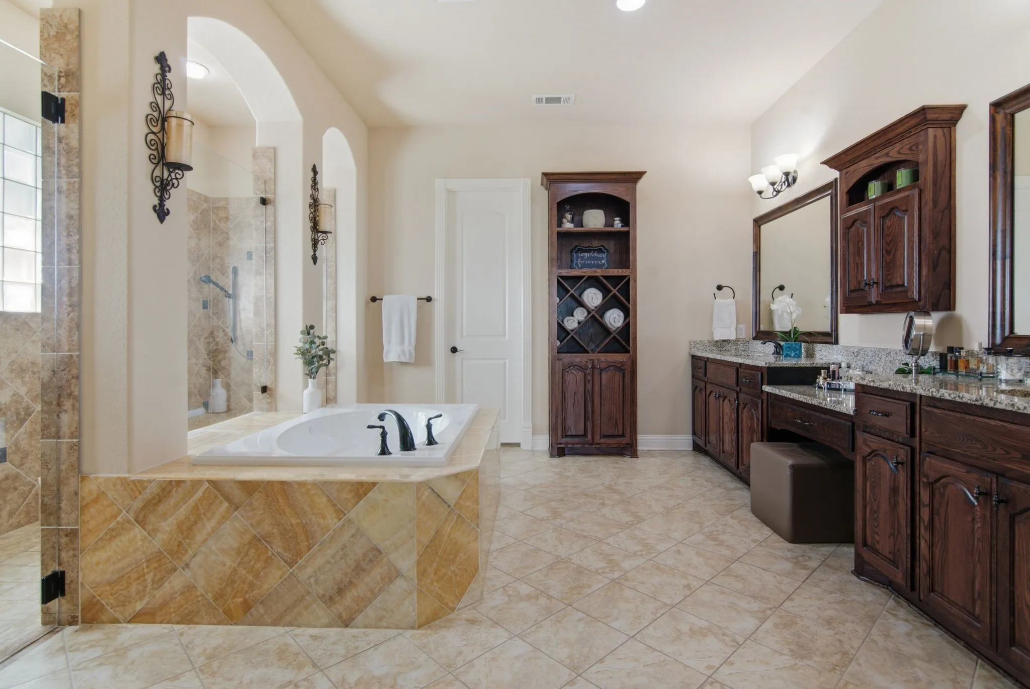 Large primary bath with dual vanities and sinks, granite counters, and beautiful wood cabinetry.