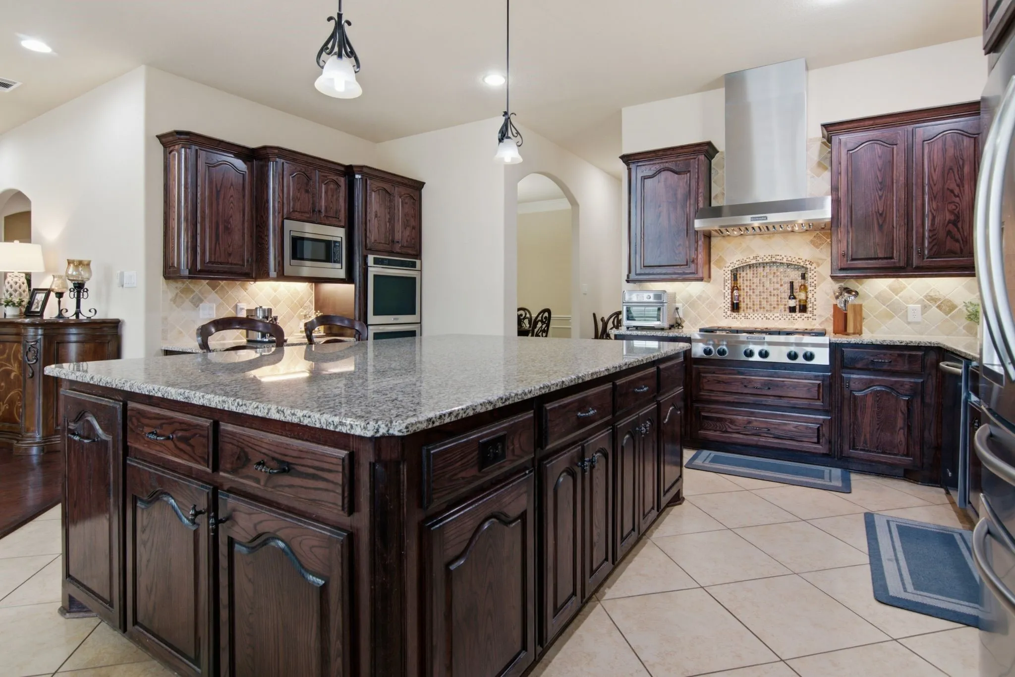 The chef’s kitchen, designed for everyday living & entertaining with expansive island, 6-burner gas cooktop, double ovens and under cabinet lighting.