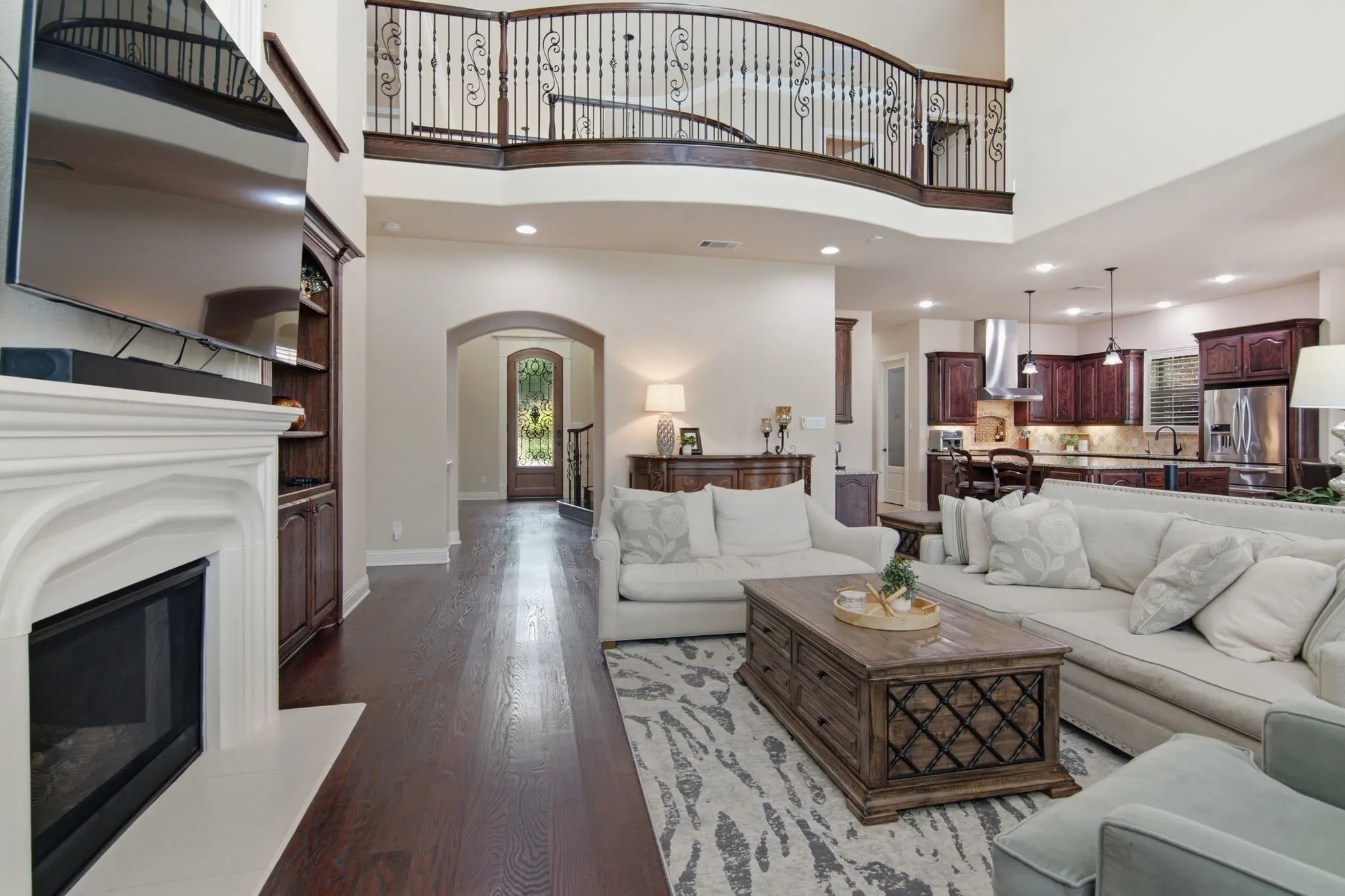 The family room is open to the kitchen and breakfast area with iron railing on the second floor.