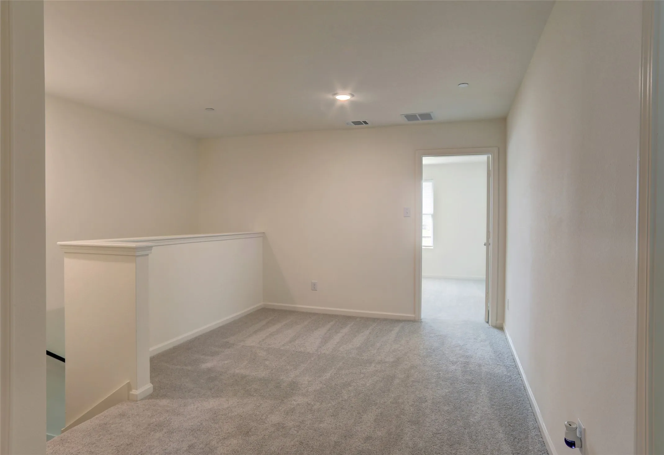 Second-story landing featuring plush gray carpeting, white trim, and a half-wall railing