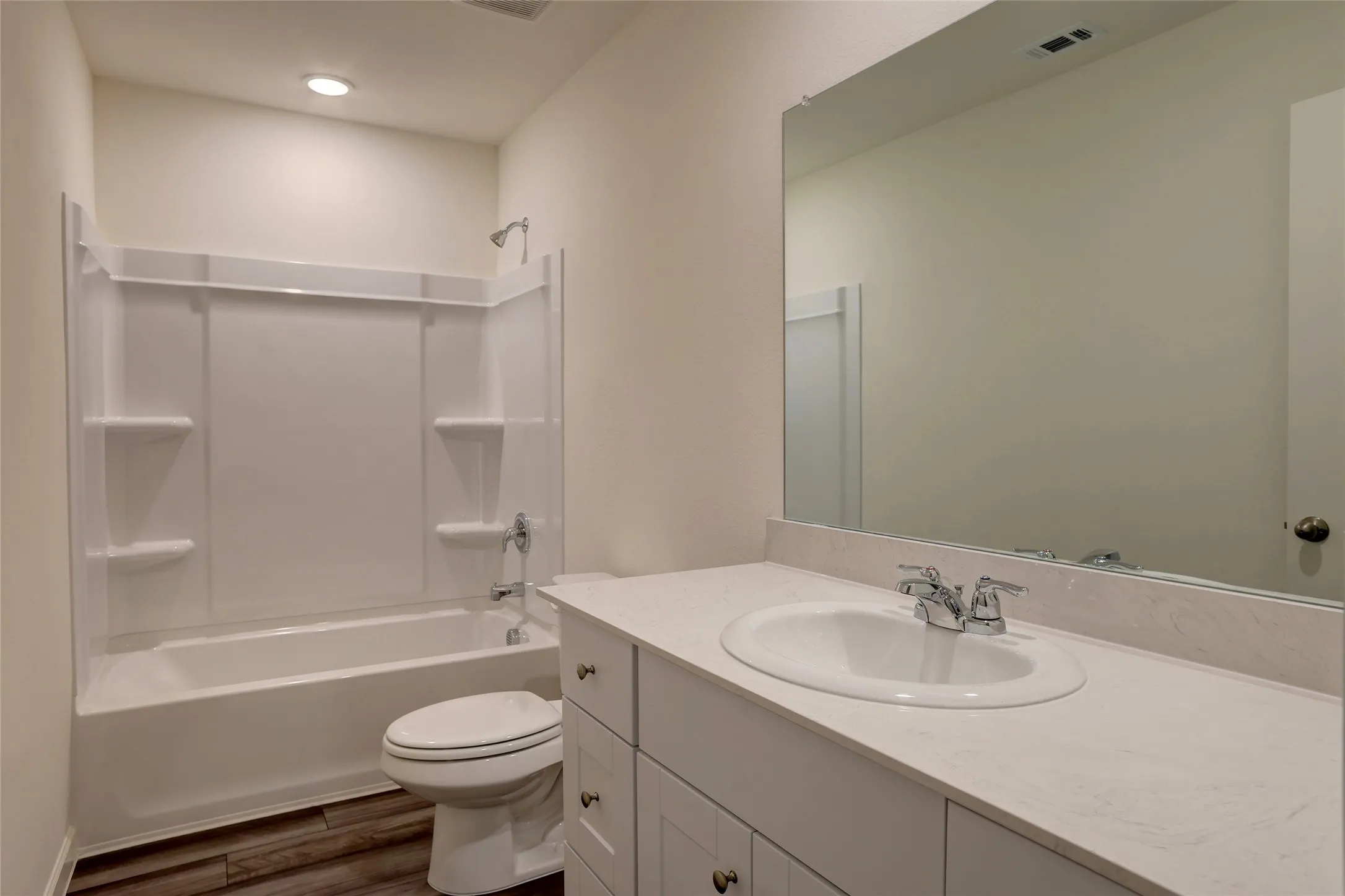 Bathroom featuring a white tub/shower combination, white vanity with an integrated sink, polished chrome faucet, and a large wall-mounted mirror