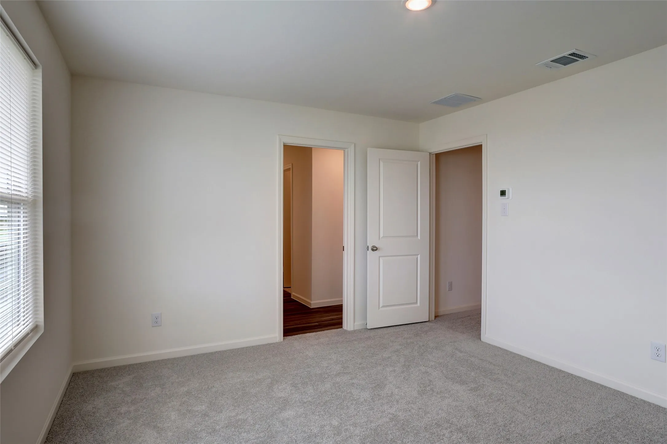Neutral wall finishes, recessed lighting, and light gray carpeting