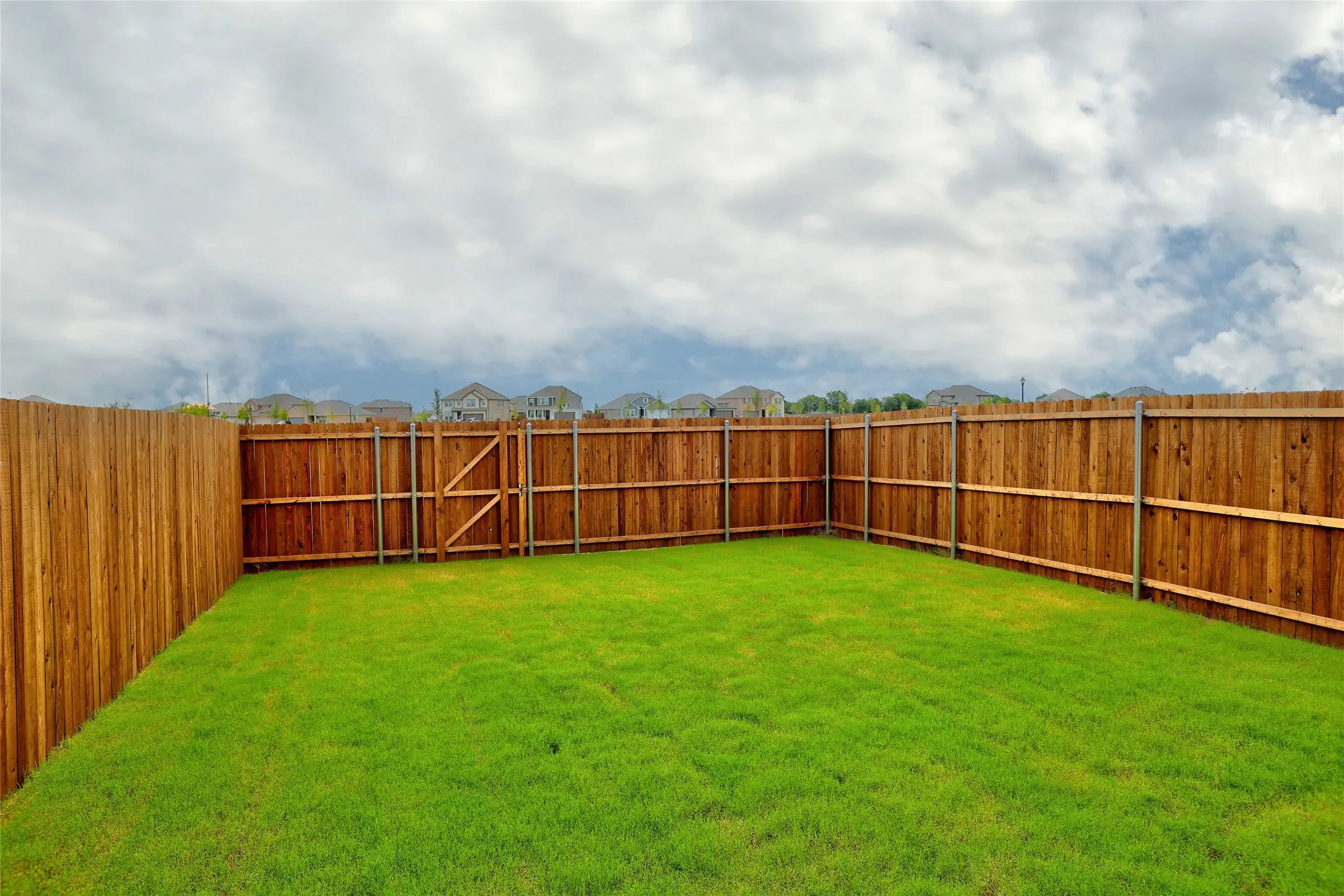 Spacious backyard featuring a lush green lawn and new wood privacy fencing