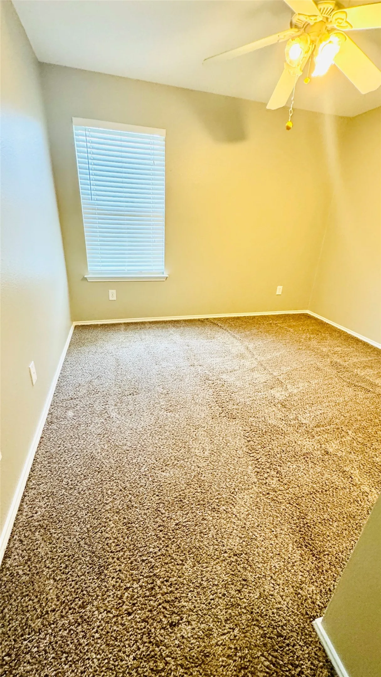 Carpeted room featuring a window with blinds, a ceiling fan with integrated lighting, and neutral wall tones