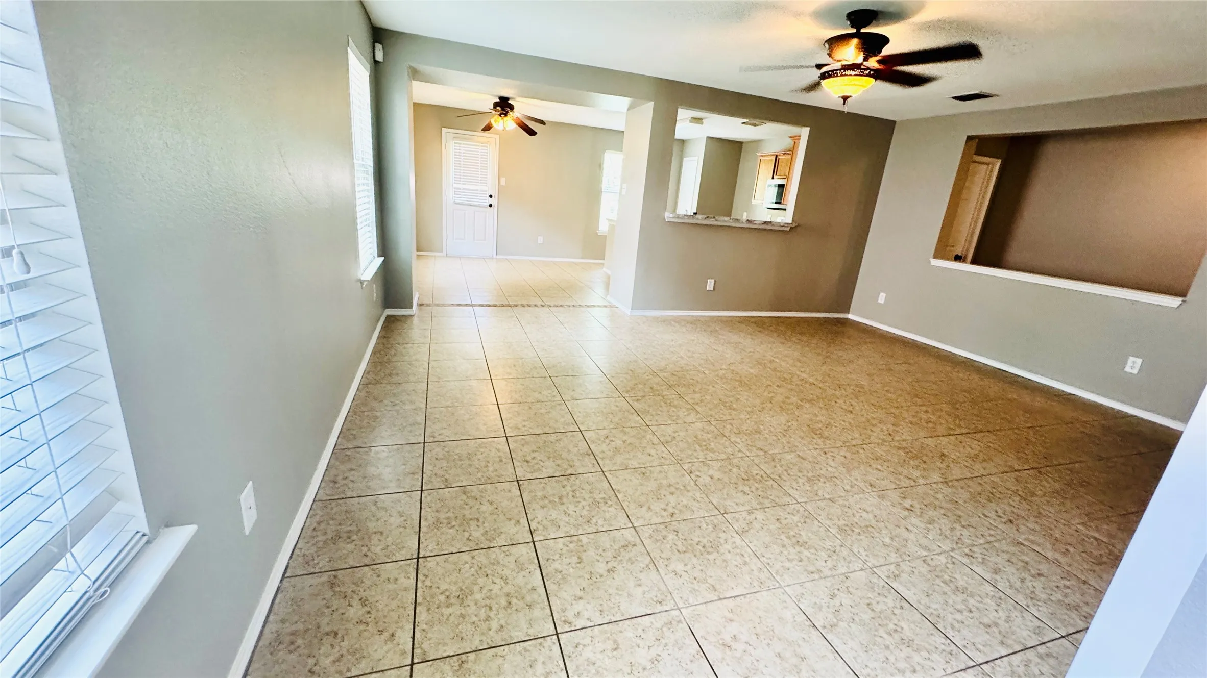 Expansive room featuring tile flooring, neutral wall tones, and multiple ceiling fans