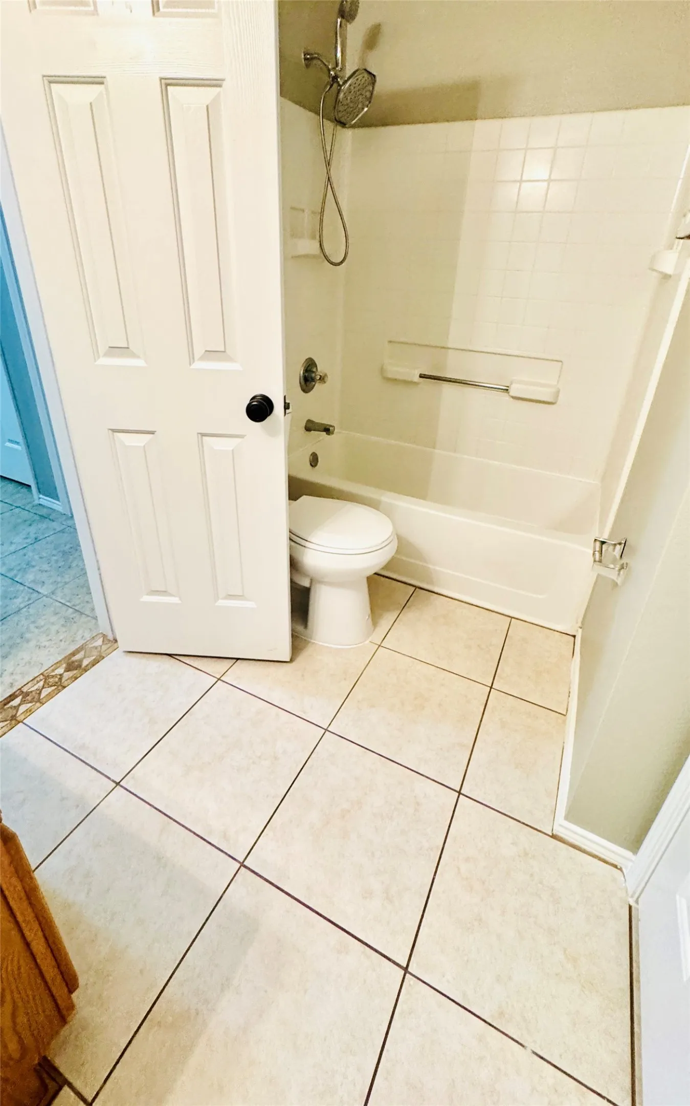 Bathroom with a white panel door and a bath-shower combination featuring a chrome shower head and faucet