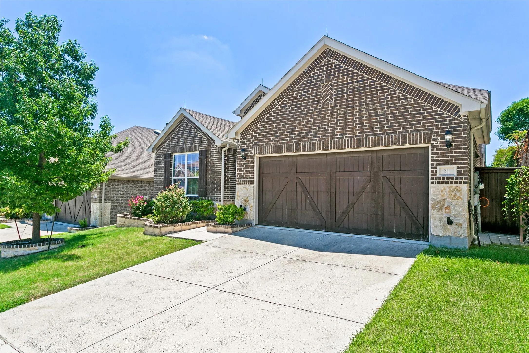Brick exterior with stone accents, featuring a two-car garage with carriage-style doors