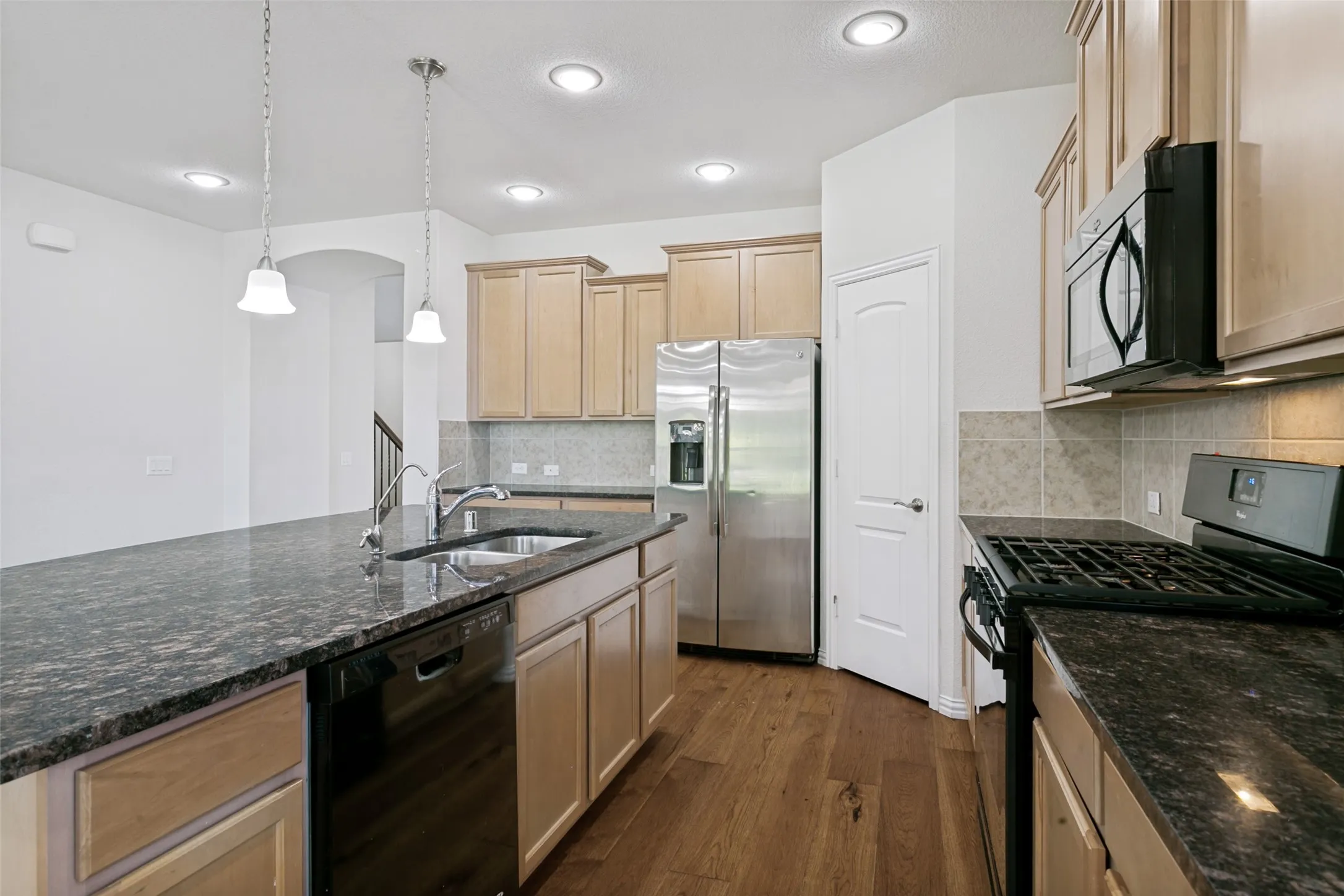 Kitchen featuring wood-finish flooring, recessed lighting, and an island with a built-in sink