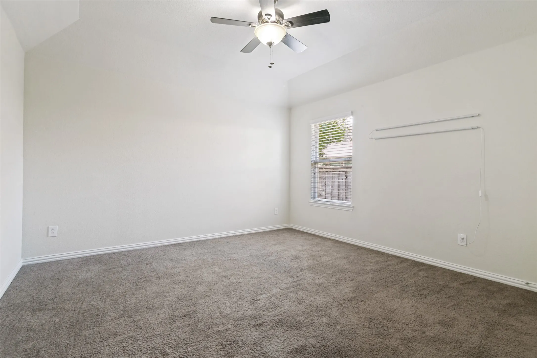 Spacious room with vaulted ceilings and neutral carpeting