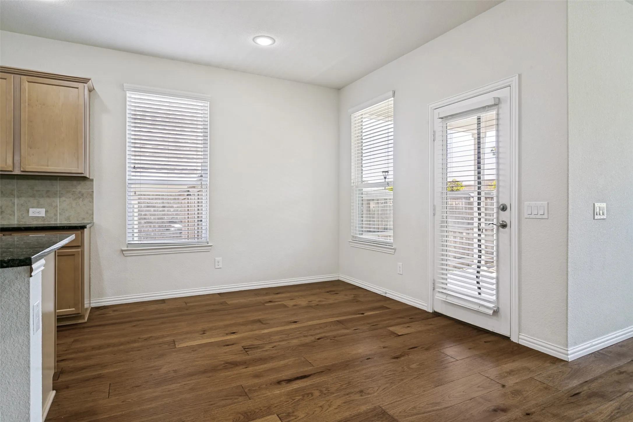 Spacious dining area featuring wood-finish flooring, recessed lighting, and white walls
