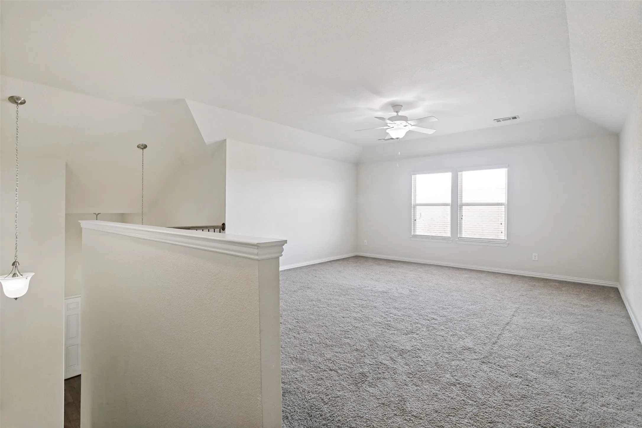 Spacious loft area featuring vaulted ceilings, plush carpeting, a dual-pane window, and a ceiling fan with integrated lighting