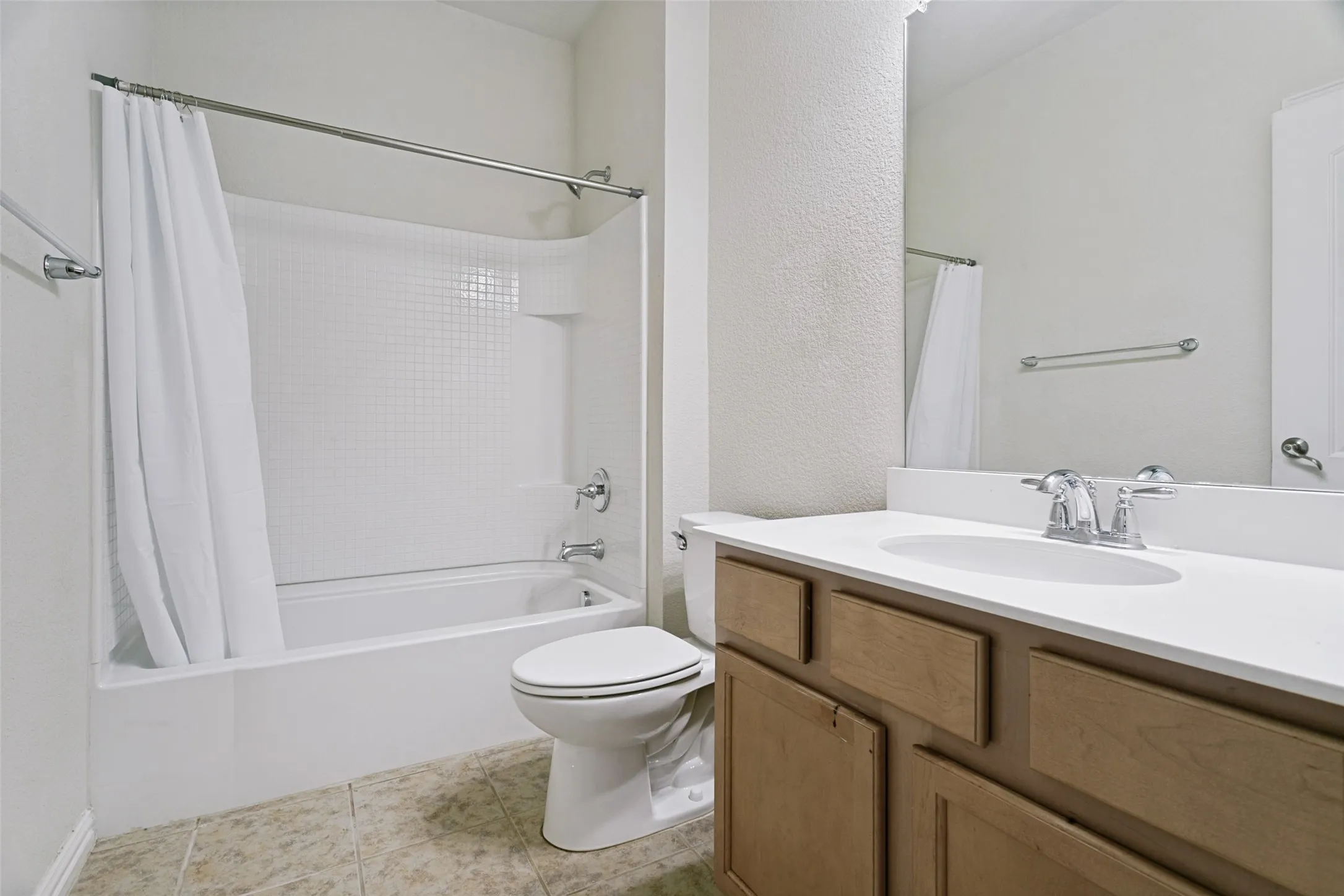 Full bathroom featuring a single vanity with wood-finish cabinetry, a white countertop, and a chrome faucet