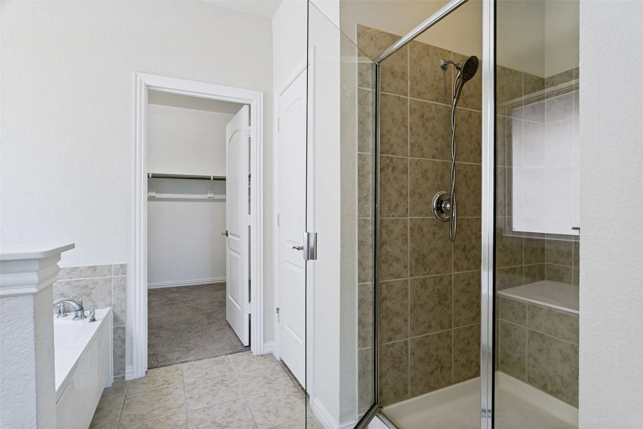 Glass-enclosed shower with tile surround and integrated bench