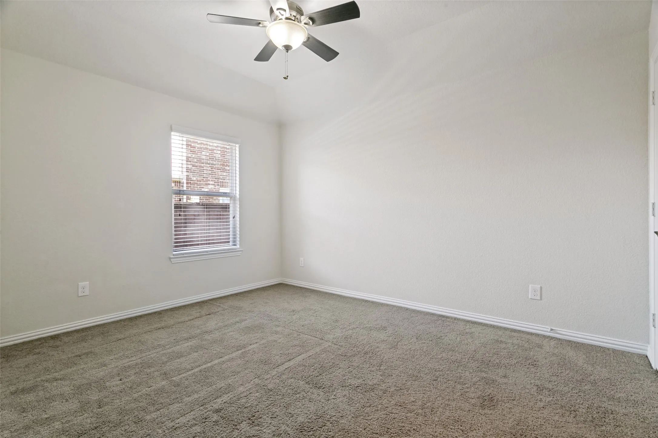Carpeted interior space featuring a ceiling fan with integrated lighting, a single window with blinds, and white trim molding
