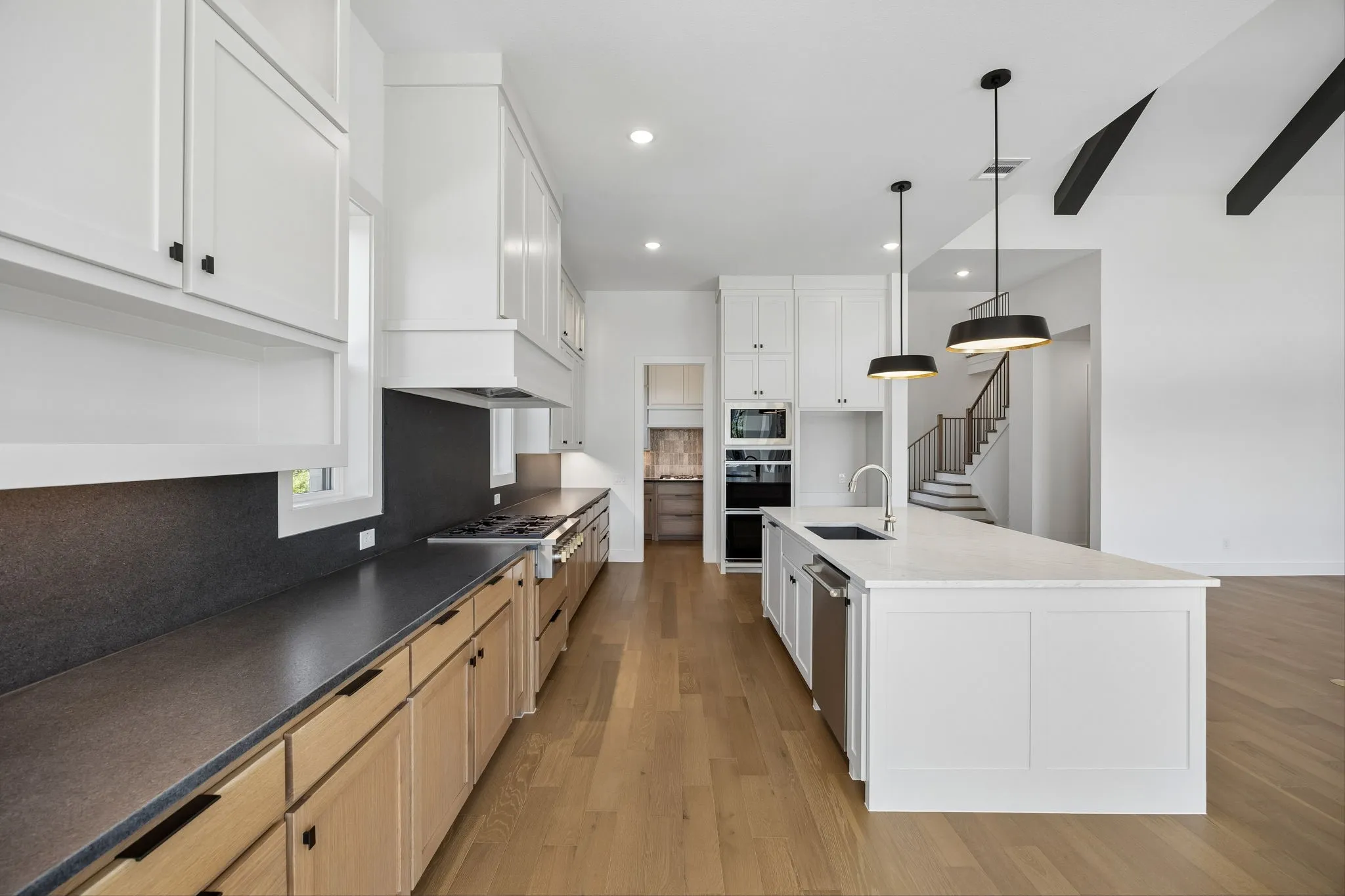 Beautiful two tone cabinetry, gorgeous countertops and a modern slab backsplash effortlessly pair with contemporary stainless steel to create a kitchen for the ages!