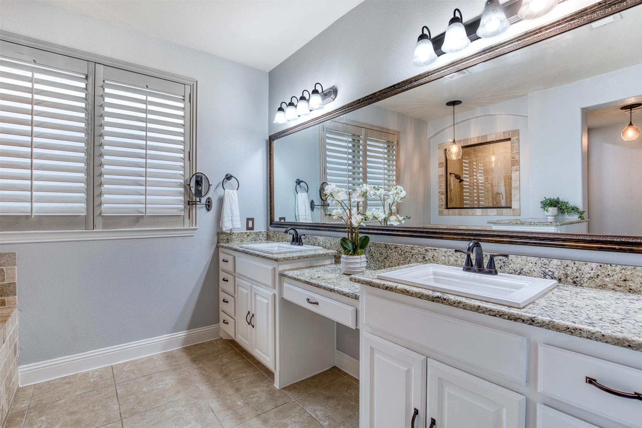 En-suite bath with dual sinks and vanity seating area.