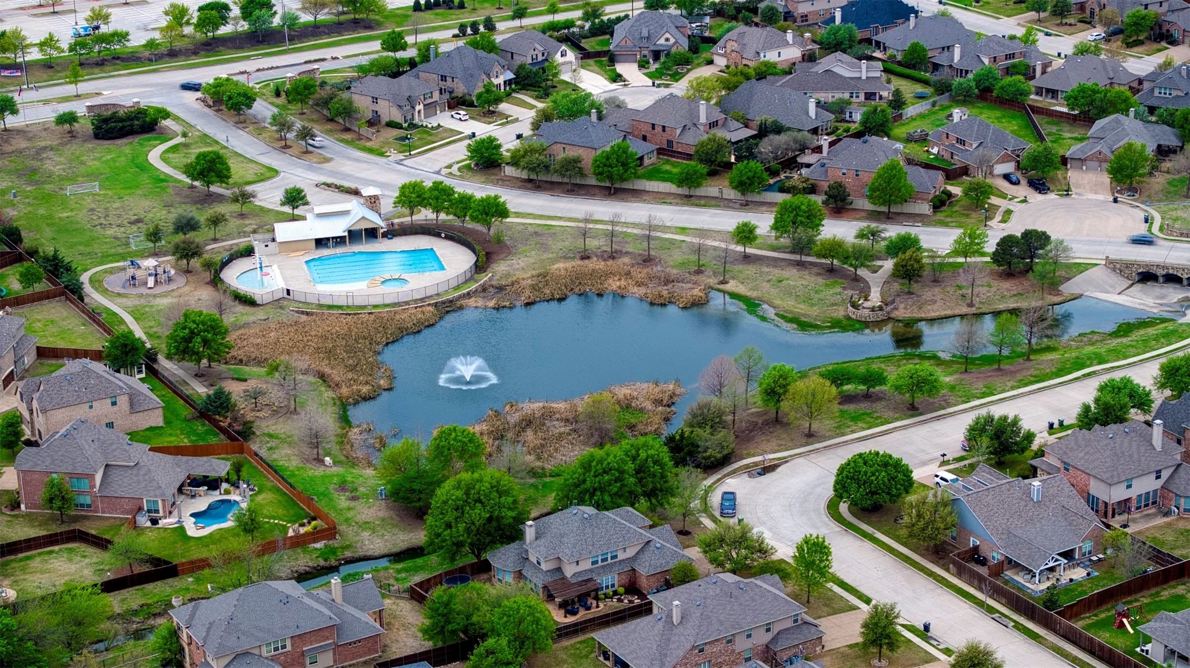 Aerial view of community with pool and pond.
