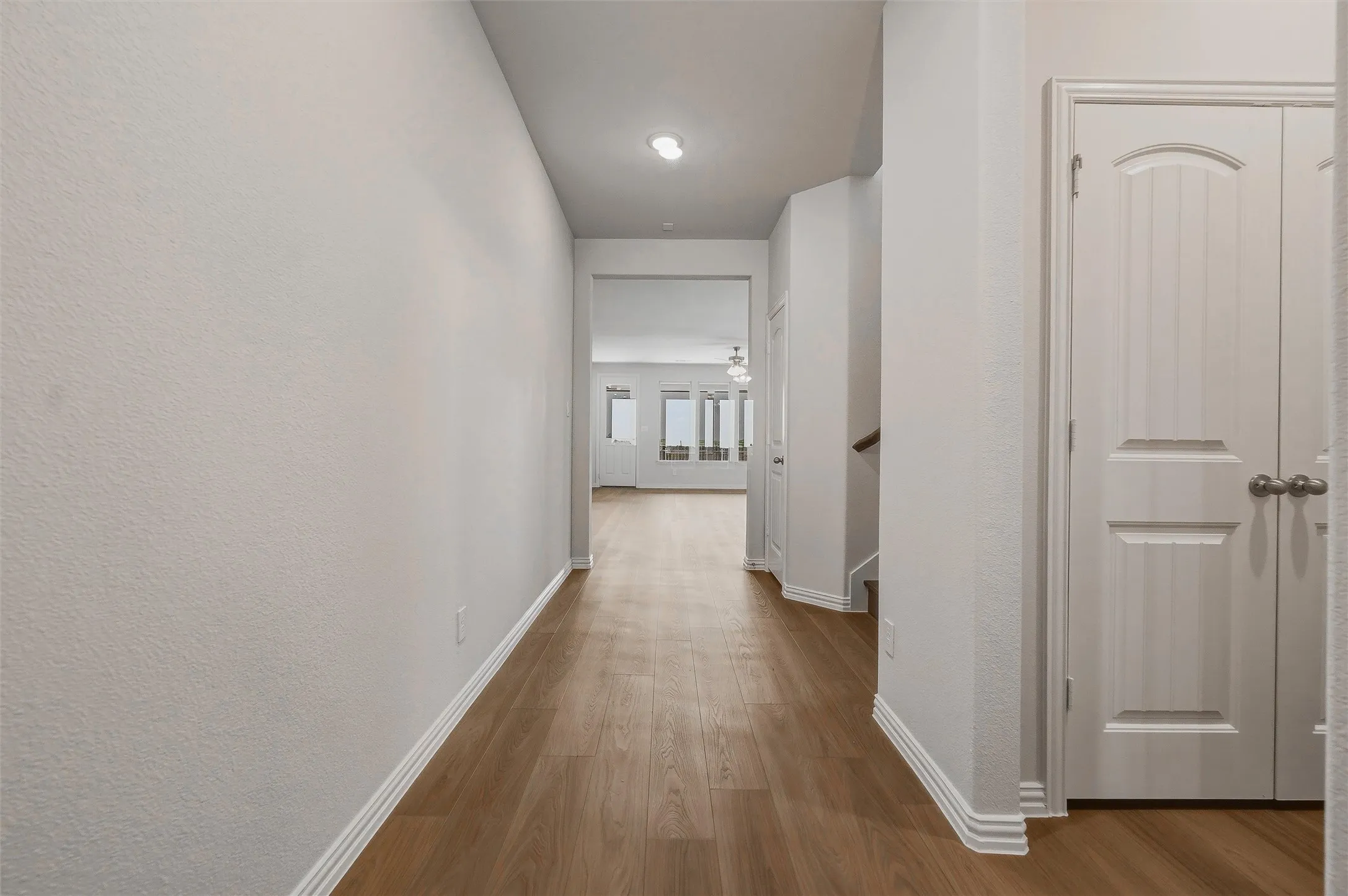 Hallway featuring wood-finish flooring, white walls, and recessed lighting