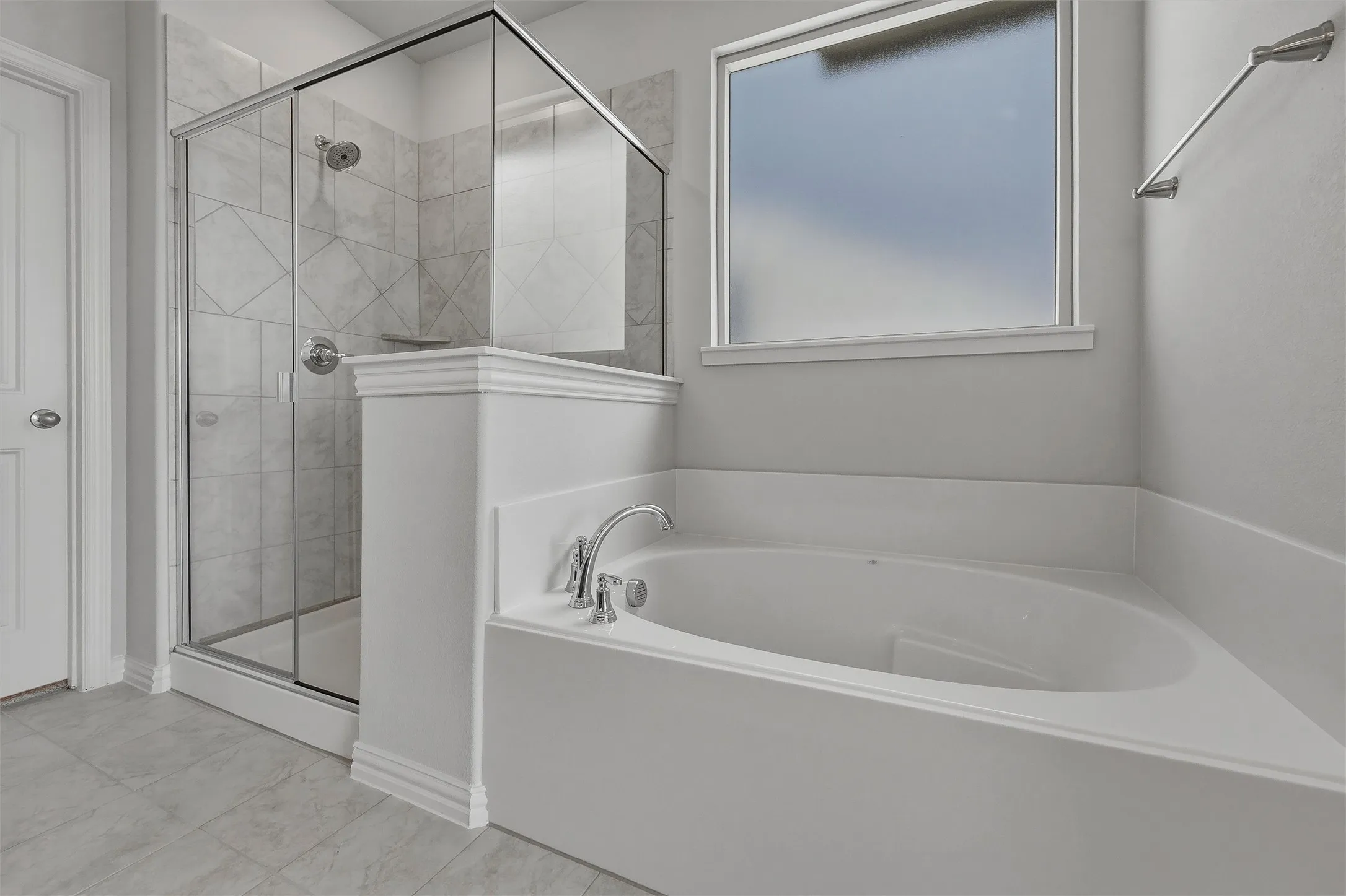 Built-in soaking tub with chrome fixtures, enclosed glass shower with tiled walls, frosted window, and tile flooring