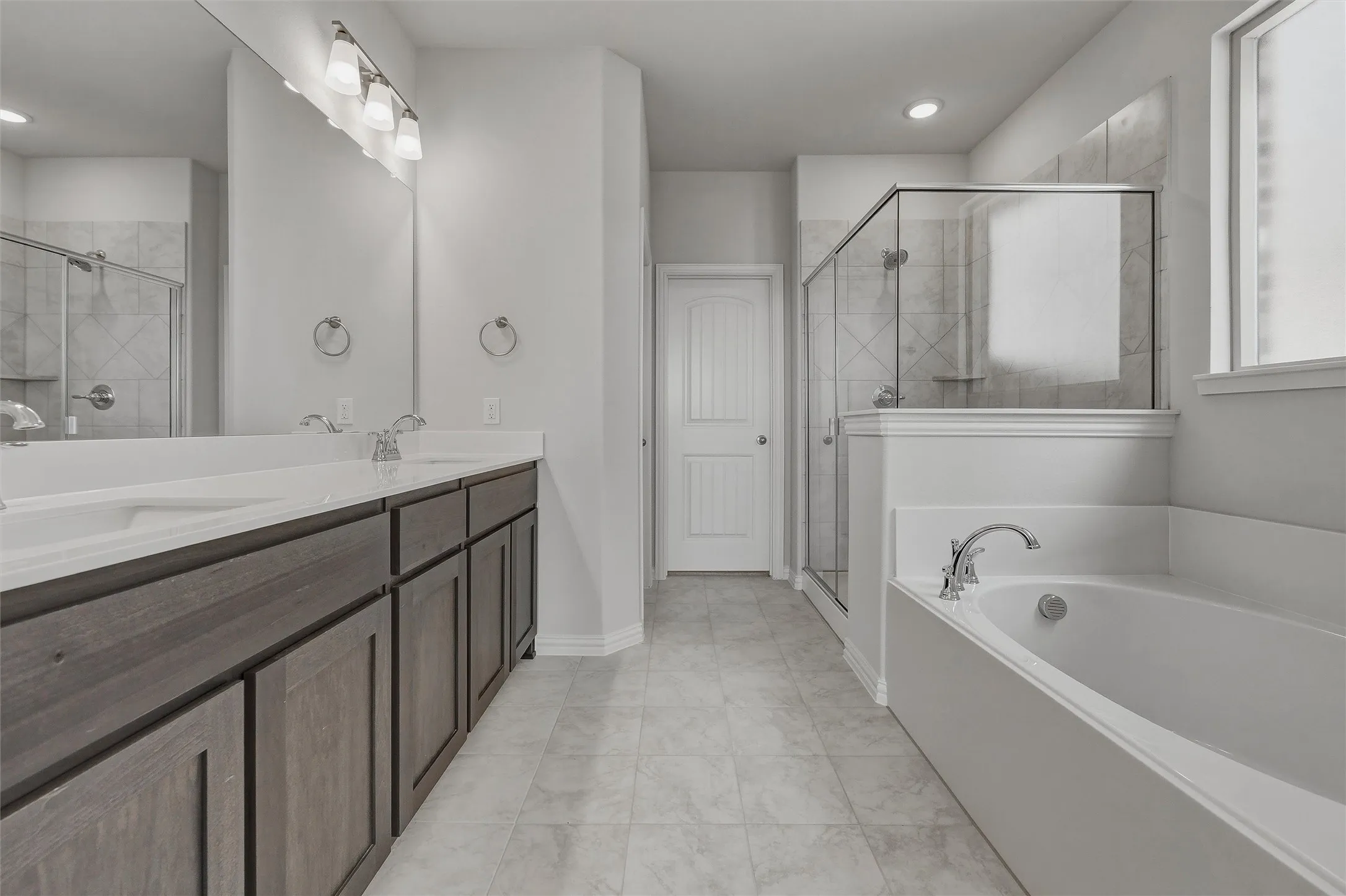 Dual vanity with white countertops, wood-finish cabinetry, and polished chrome fixtures