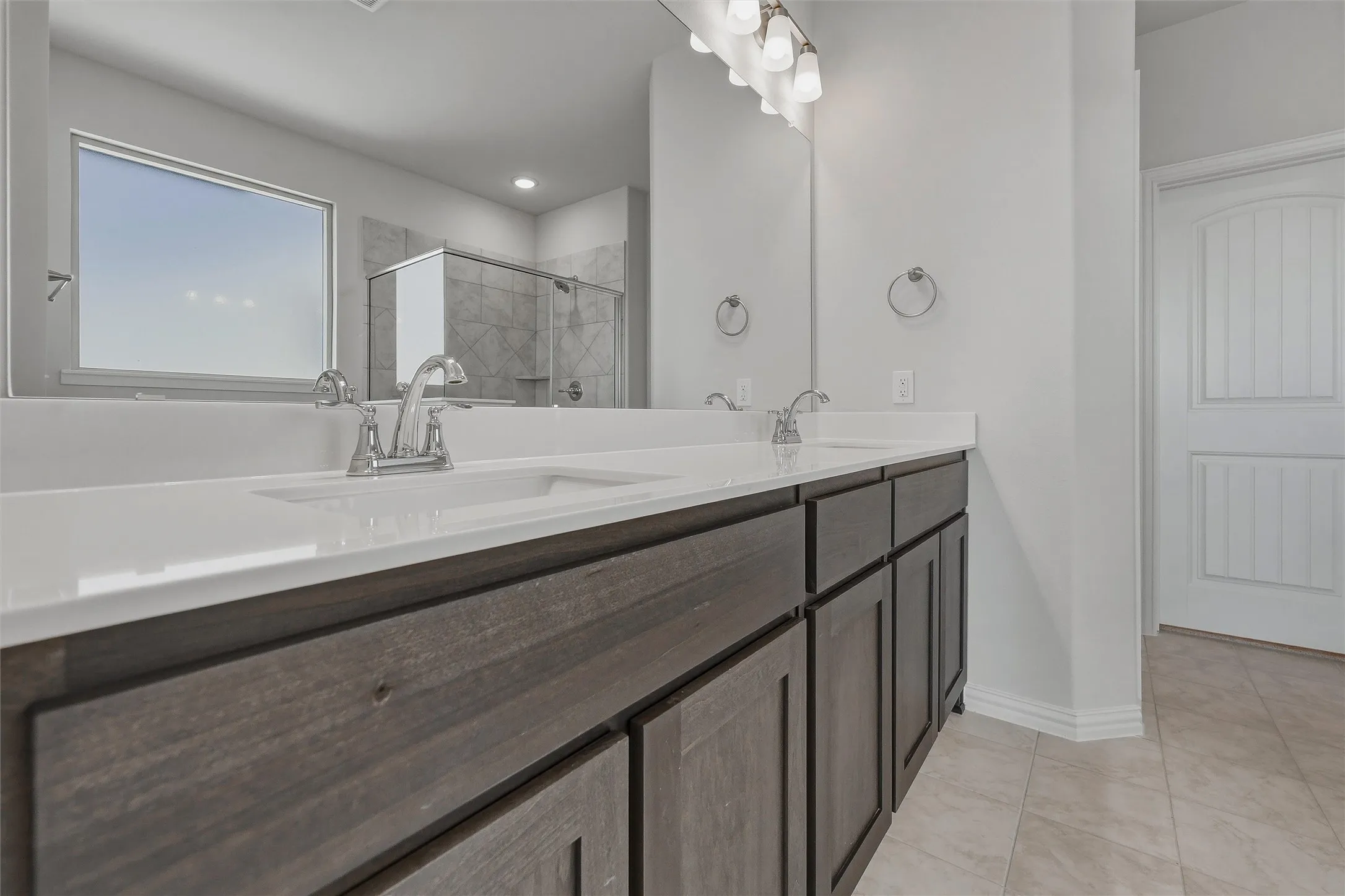Dual vanity with white countertops, undermount sinks, and wood-finish cabinetry