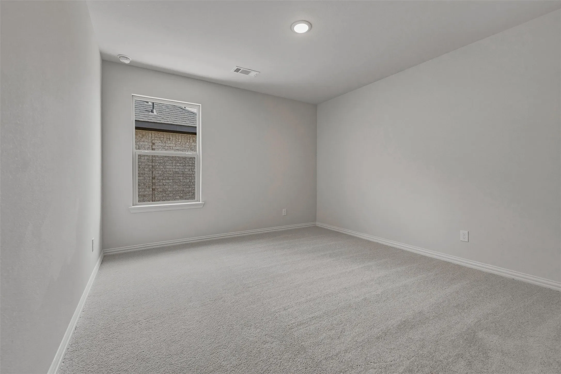 Recessed ceiling lighting, light gray wall finishes, gray carpet flooring, and a double-hung window