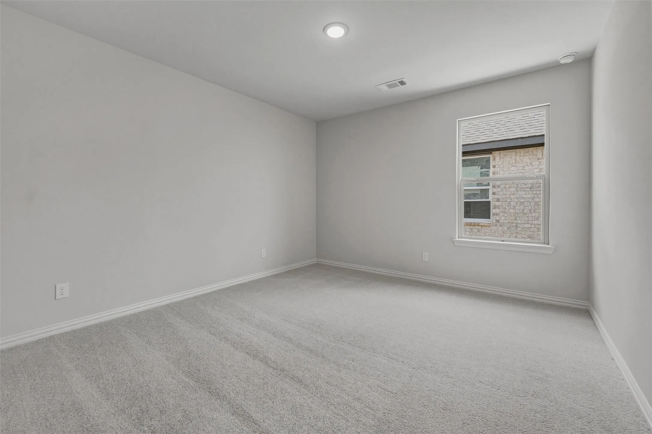 Soft gray carpeting with white trim, recessed ceiling lighting, and a window with white casing